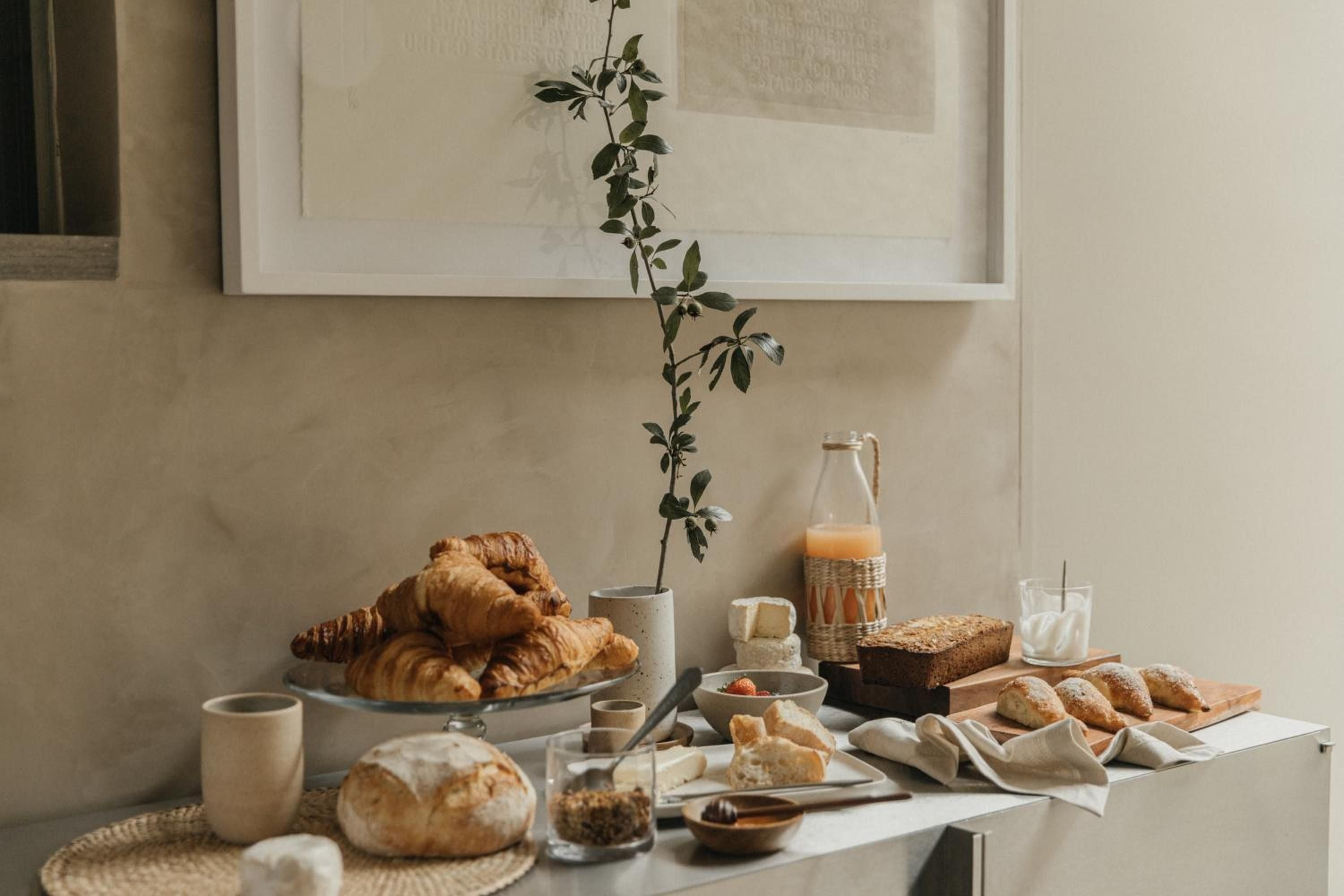 Morning light bathes an artfully arranged breakfast spread of golden croissants, rustic bread, and fresh juice—a feast that embodies the casa's unhurried elegance.