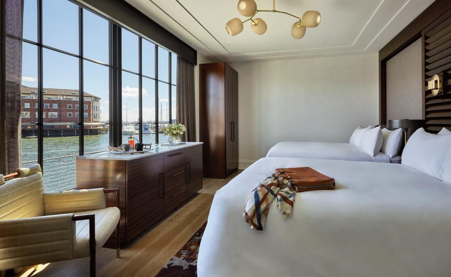 Floor-to-ceiling windows frame Baltimore's Inner Harbor from this waterfront suite, where rich walnut millwork and brass globe lighting create intimate luxury above the marina.