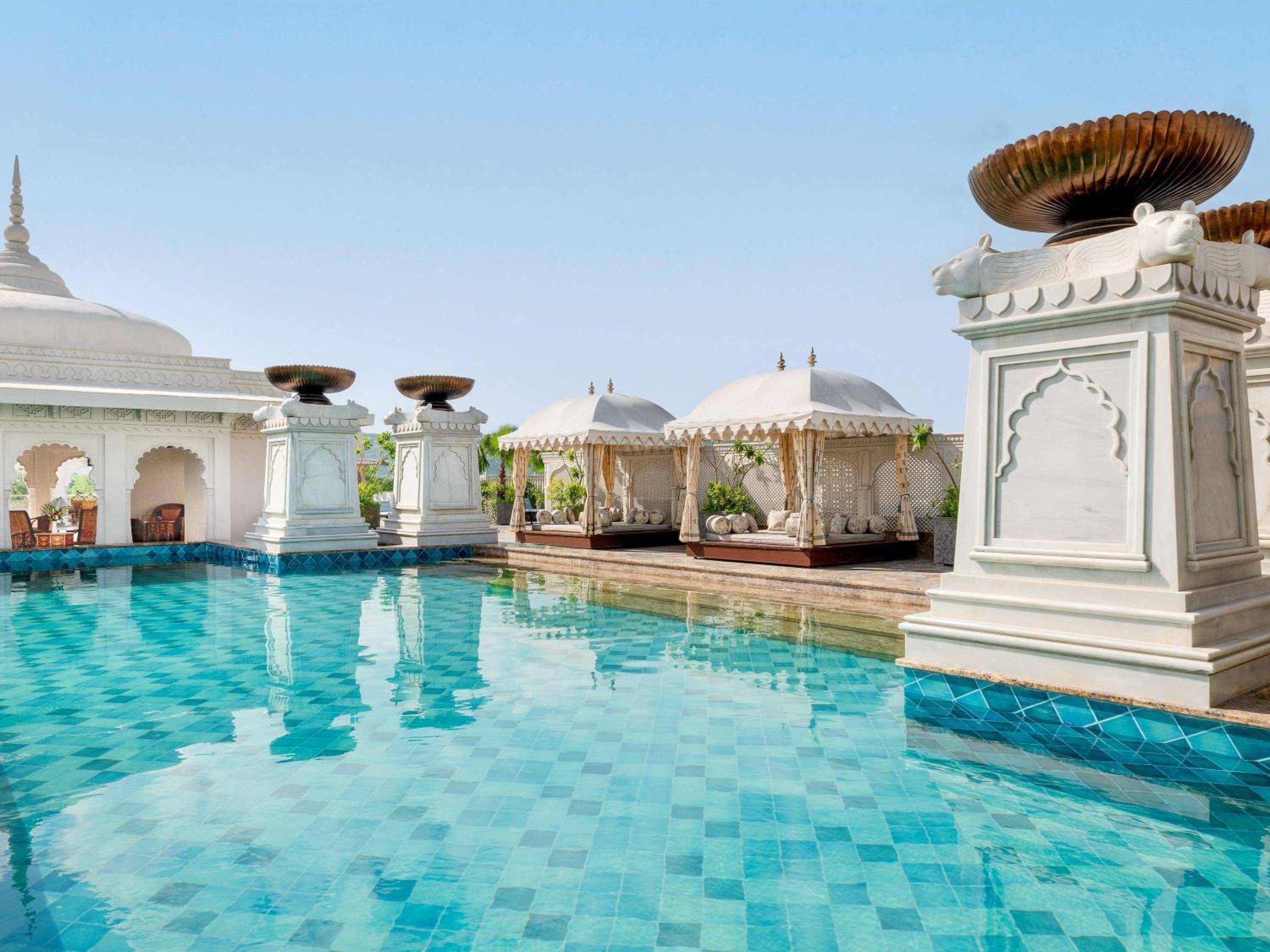 Marble pavilions crowned with copper umbrellas frame the azure pool, where Rajasthani palatial architecture meets contemporary luxury in perfect harmony.