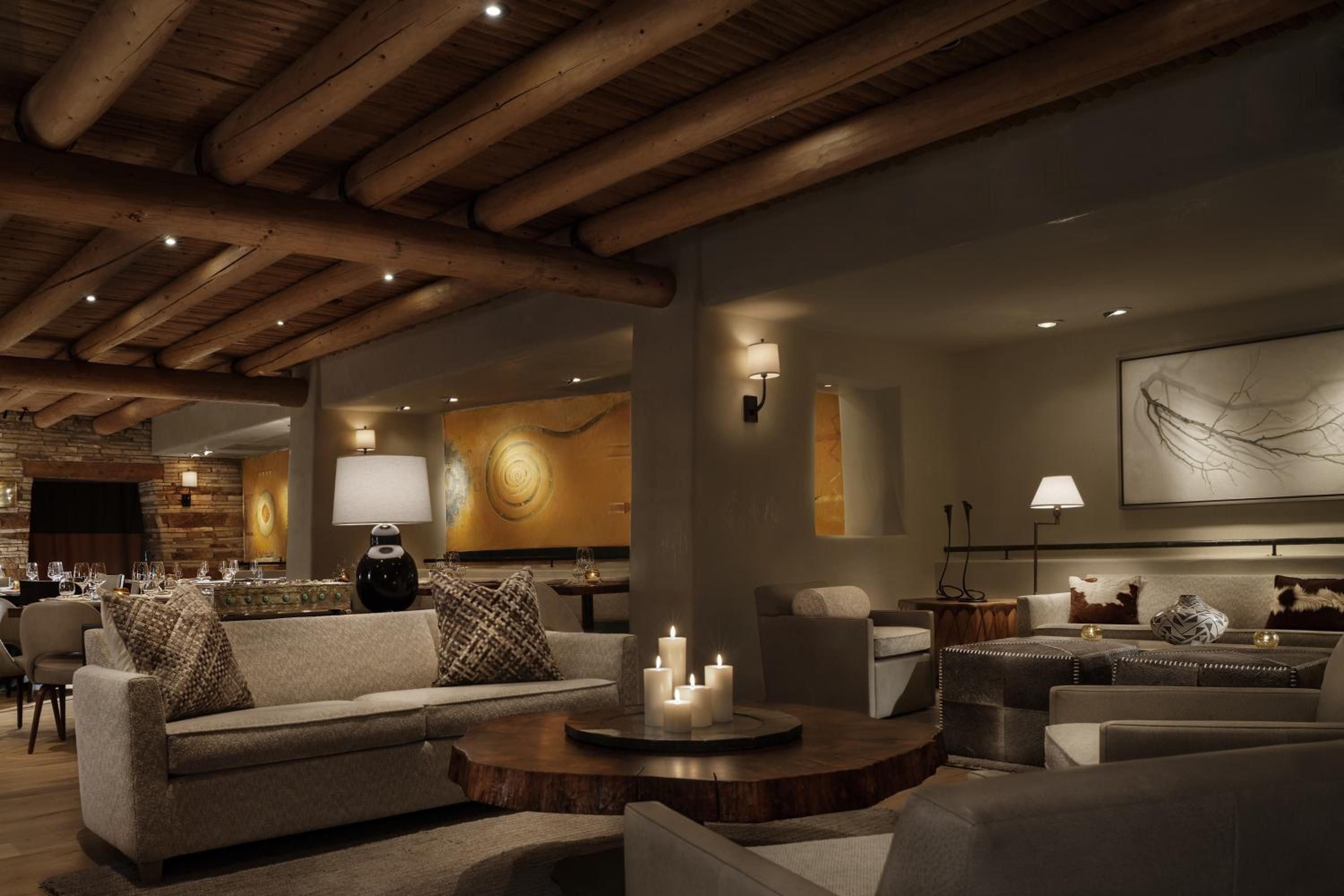 Exposed timber beams and warm candlelight create an intimate Southwest sanctuary where handwoven textiles and raw wood tables invite lingering conversations over fine wine.