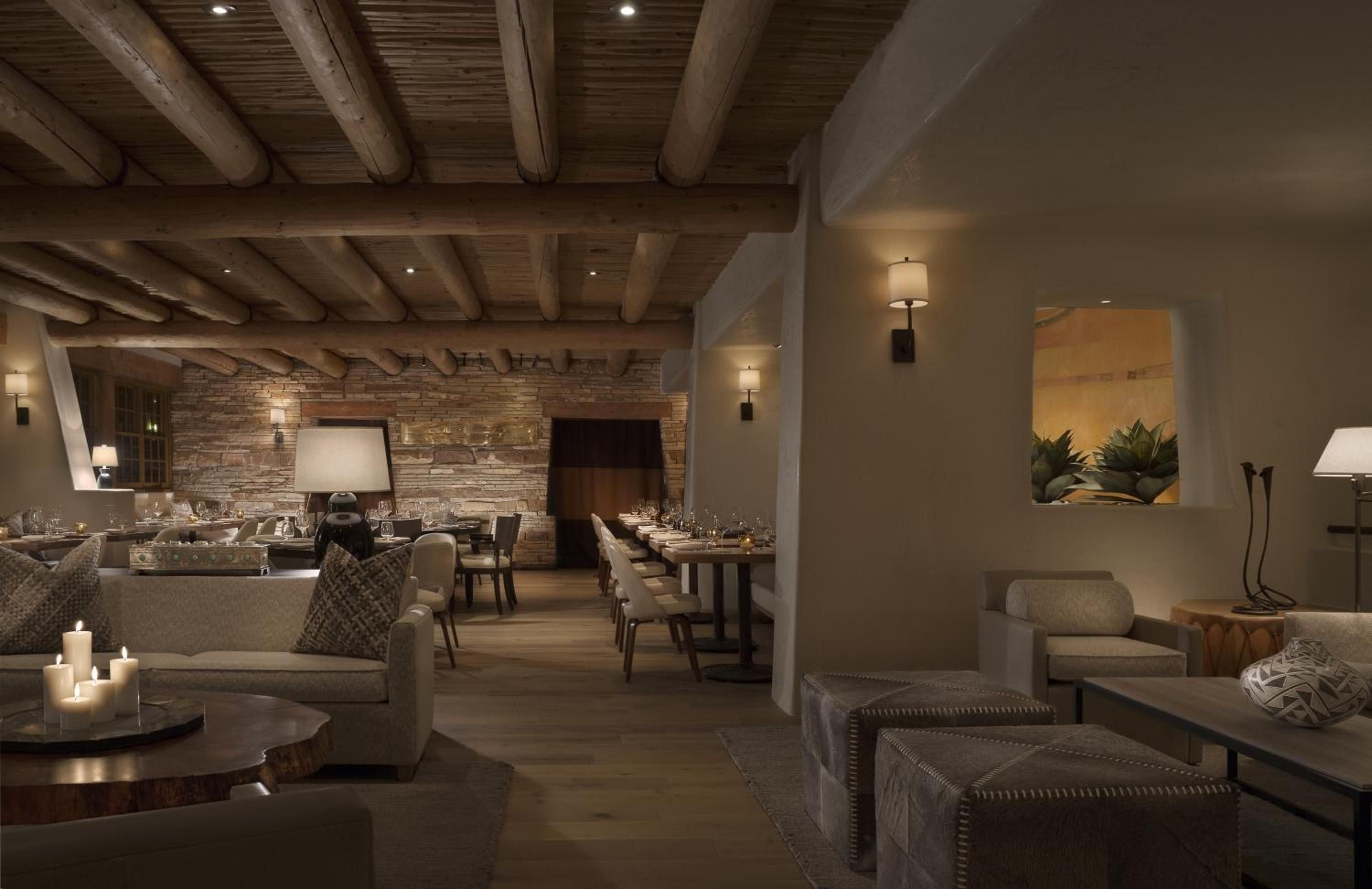 Exposed wooden beams and flickering candles create intimate dining alcoves where Southwestern cuisine meets refined hospitality beneath ancient-inspired architecture.