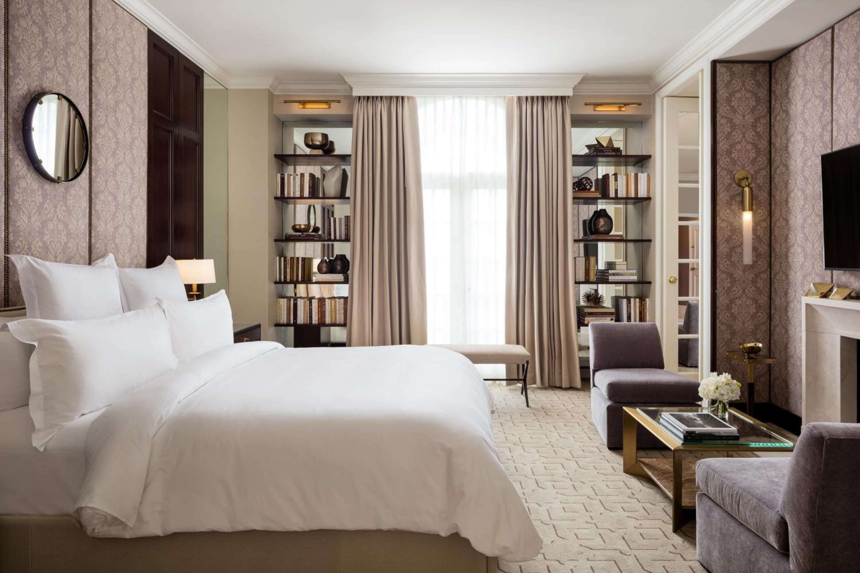 Curated bookshelves frame floor-to-ceiling windows while plush velvet seating and brass accents create an intimate library-inspired retreat with sophisticated residential warmth.