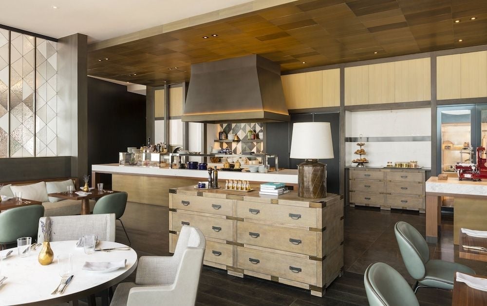 Open kitchens and warm wood tones create an intimate culinary theater where sage-green banquettes frame the sophisticated dining experience at this elevated Phnom Penh destination.