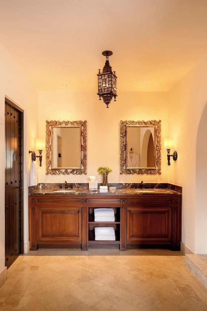 Handcrafted Moroccan lanterns cast golden light across marble countertops and ornate mirrors, creating an intimate sanctuary that marries Old World craftsmanship with modern luxury.