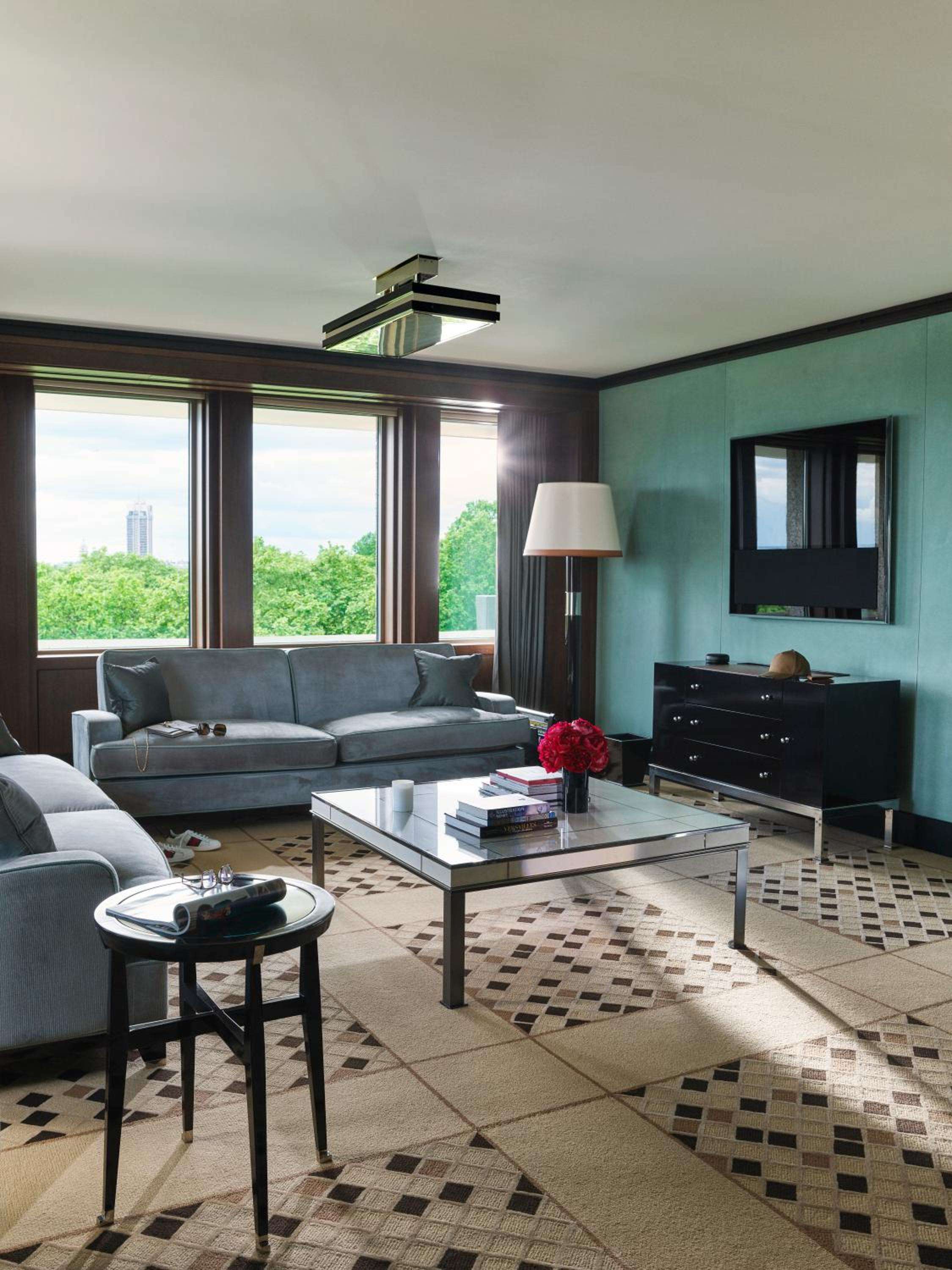 Charcoal velvet seating and mint-green walls create a sophisticated sanctuary, while floor-to-ceiling windows frame Hyde Park's verdant canopy in this elegantly appointed suite.