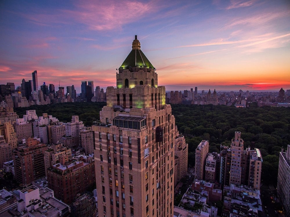 Manhattan's Upper East Side glows in twilight hues as The Carlyle's iconic tower rises majestically above Central Park's verdant canopy.