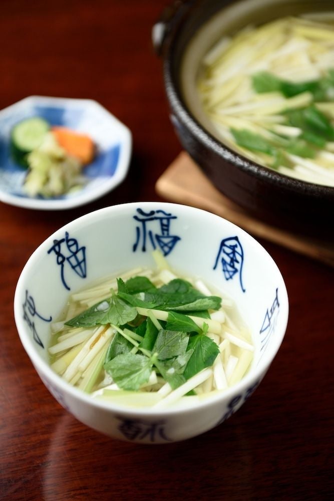 Delicate udon noodles swim in golden broth, garnished with fresh greens in hand-painted ceramic bowls that speak to centuries of Japanese culinary artistry.