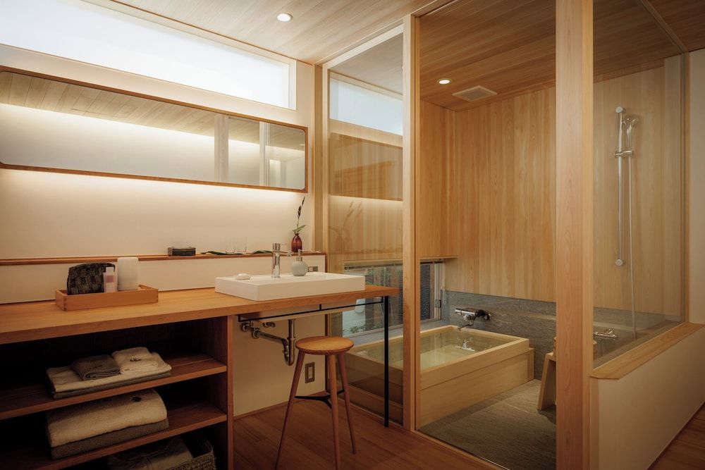 Warm hinoki wood envelops every surface in this Japanese-style bathroom, where soaking tubs and rainfall showers create a meditative spa-like sanctuary.