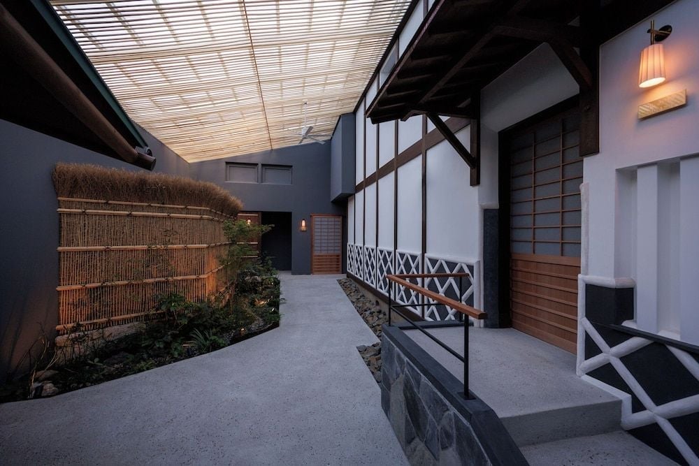 Bamboo screens and smooth concrete pathways guide guests through serene courtyards where traditional Japanese architecture meets contemporary minimalism under soft twilight.