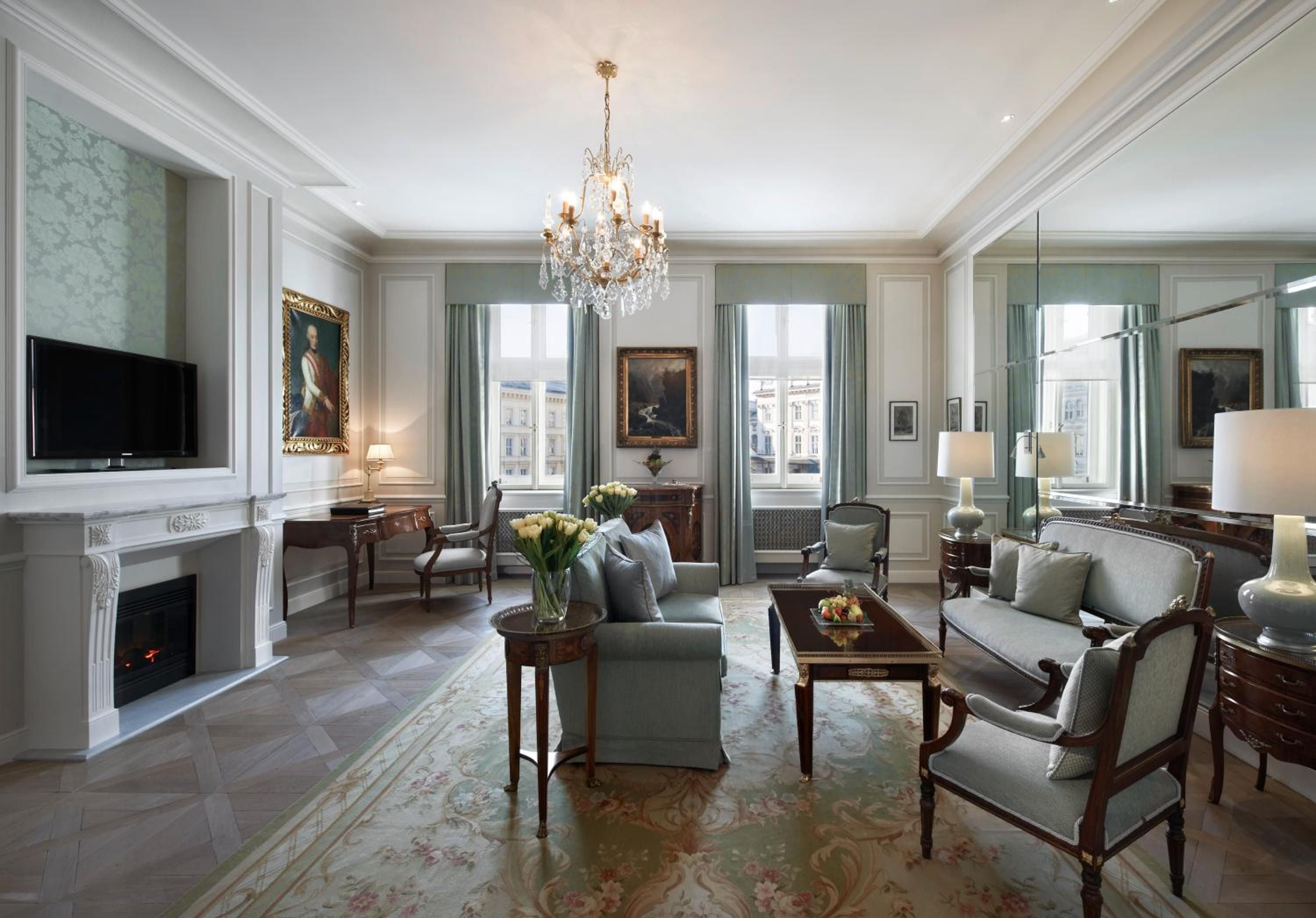 Crystal chandelier light dances across sage silk walls and mahogany furnishings in this palatial suite, where Old World portraits witness conversations over champagne and Austrian pastries.