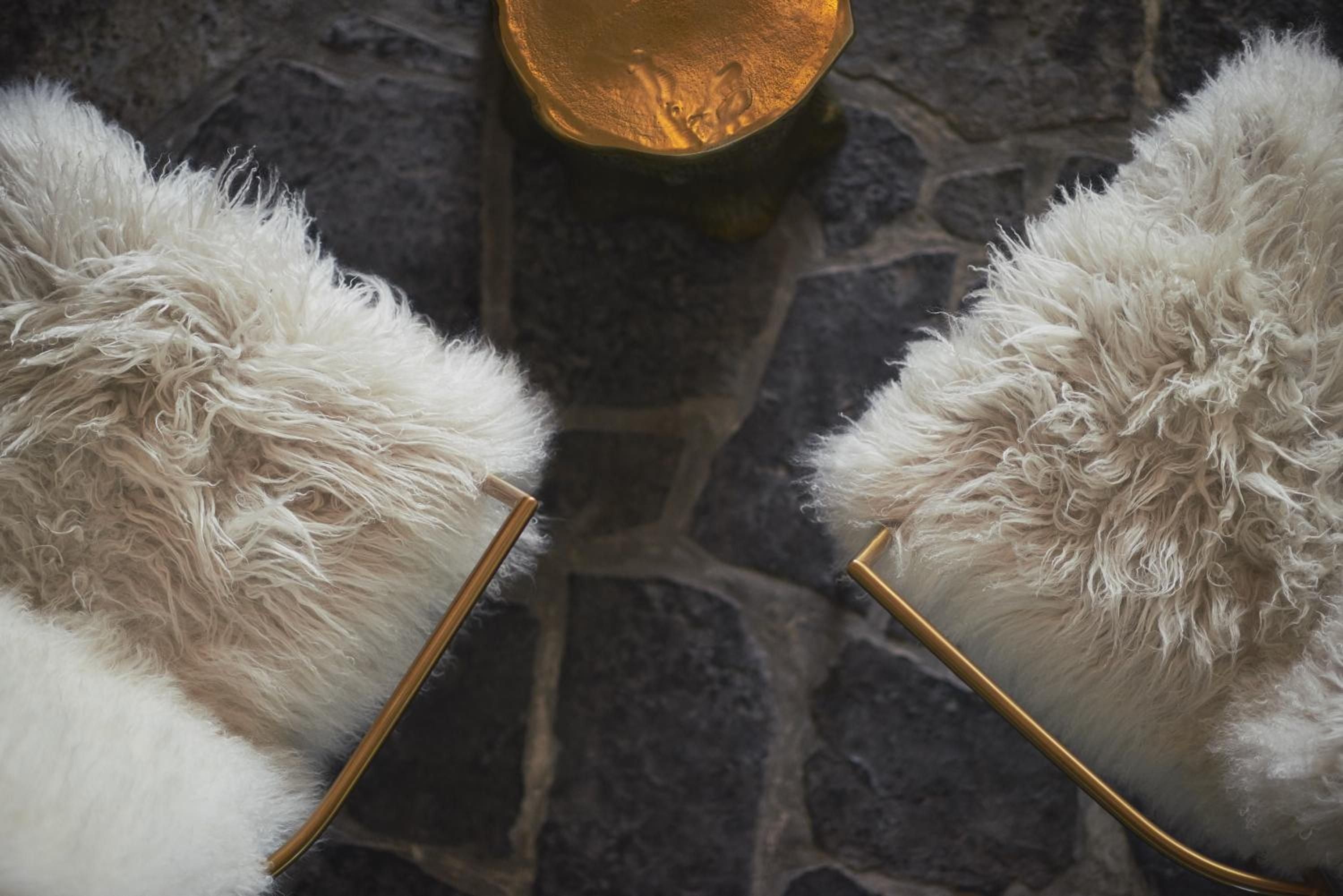 Luxurious shearling slippers with gleaming brass accents rest on weathered stone floors, embodying the property's seamless blend of rustic charm and sophisticated comfort.