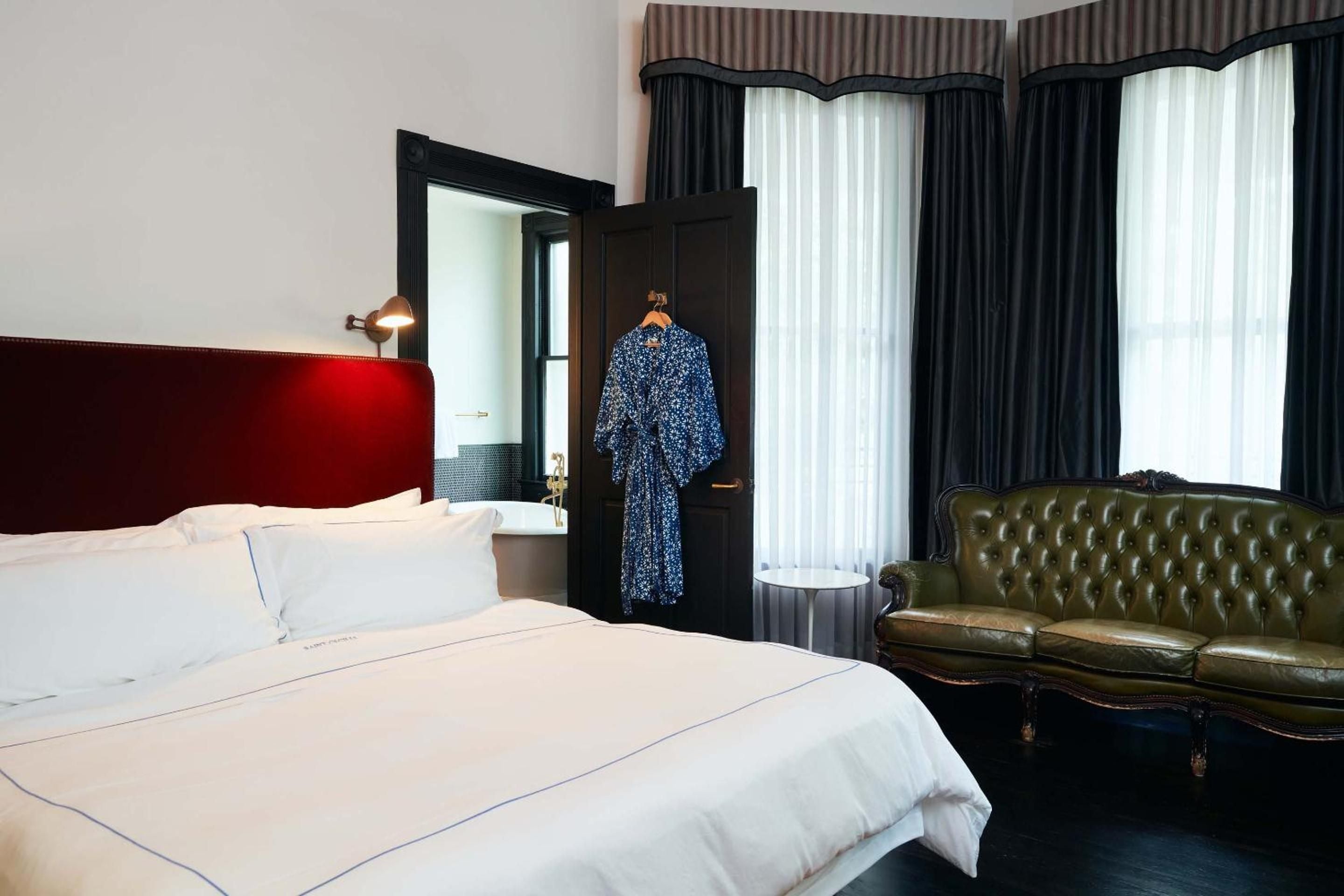 Crimson velvet headboards and emerald Chesterfield sofas create an intimate sanctuary where rock-and-roll glamour meets refined comfort in this thoughtfully appointed guest room.