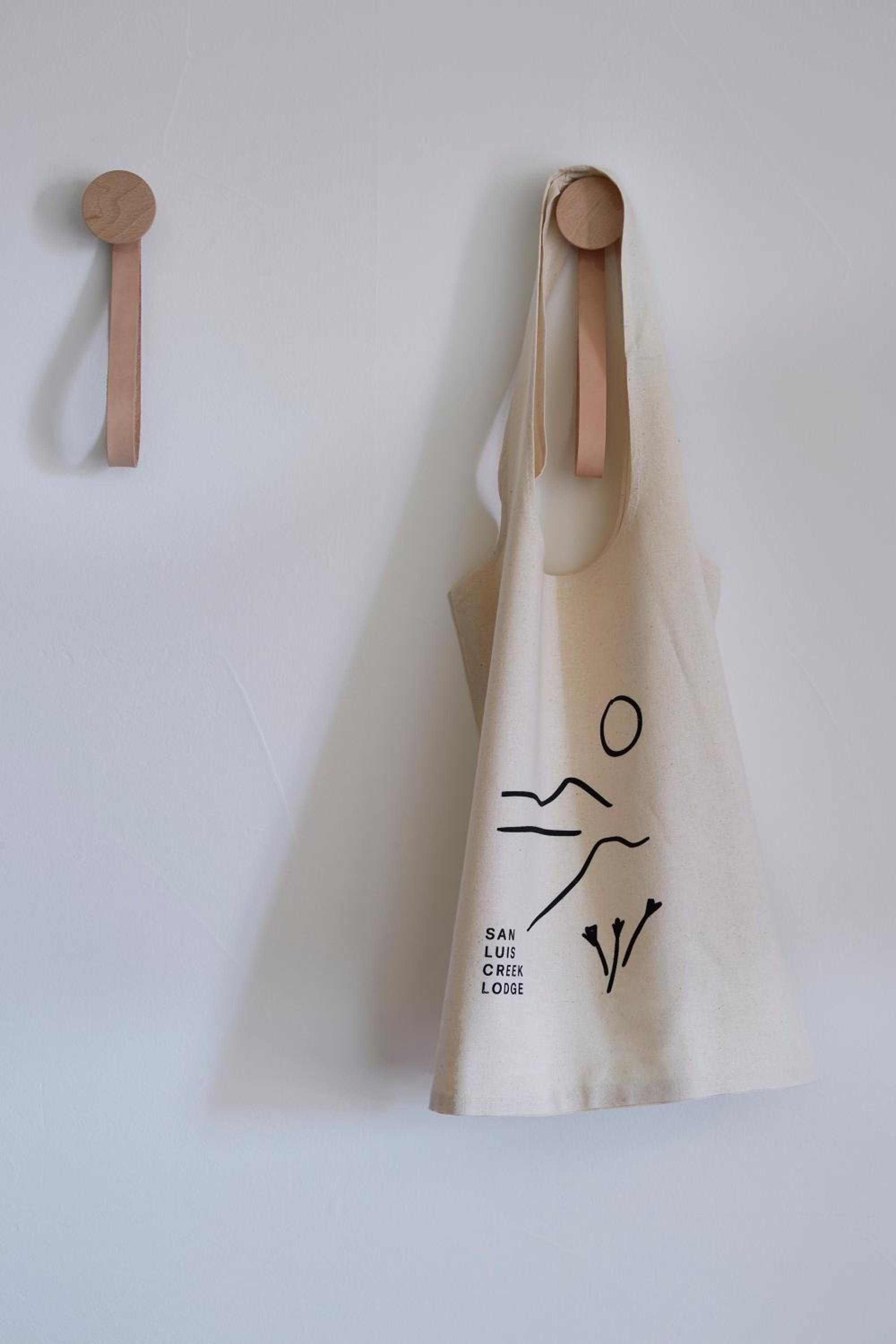 Minimalist wooden wall hooks showcase the lodge's understated elegance, where natural materials and clean lines create spaces that feel both refined and welcomingly uncluttered.