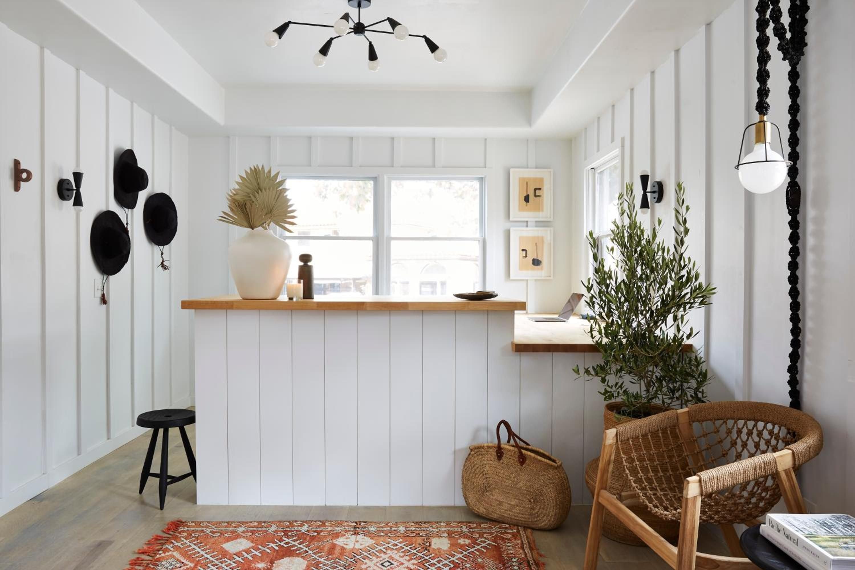 Woven textures and warm wood tones create an intimate nook where morning light filters through white-framed windows, illuminating carefully curated ceramics and dried botanicals.
