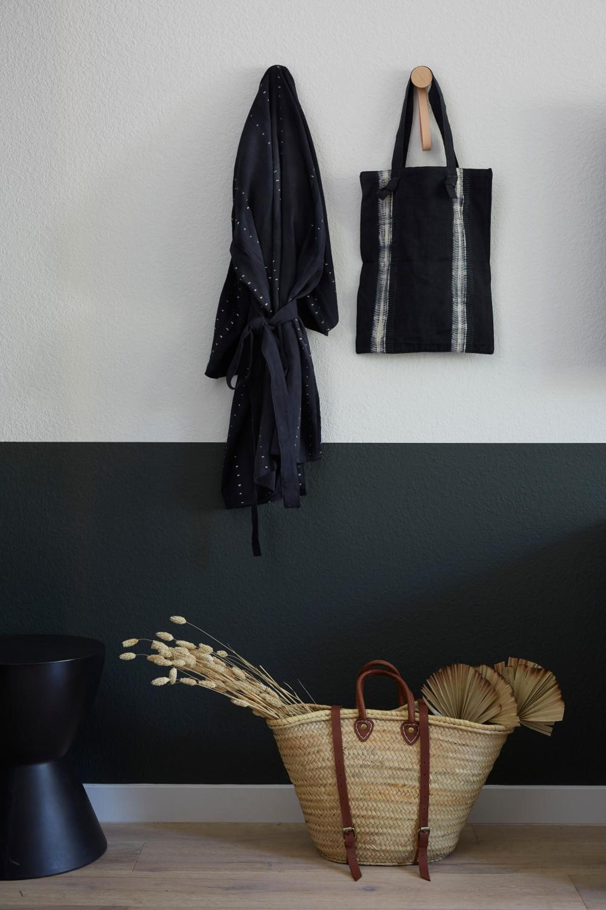 Thoughtful wall hooks display a star-dotted wrap and striped tote above a woven basket filled with dried botanicals, creating intimate storage moments.