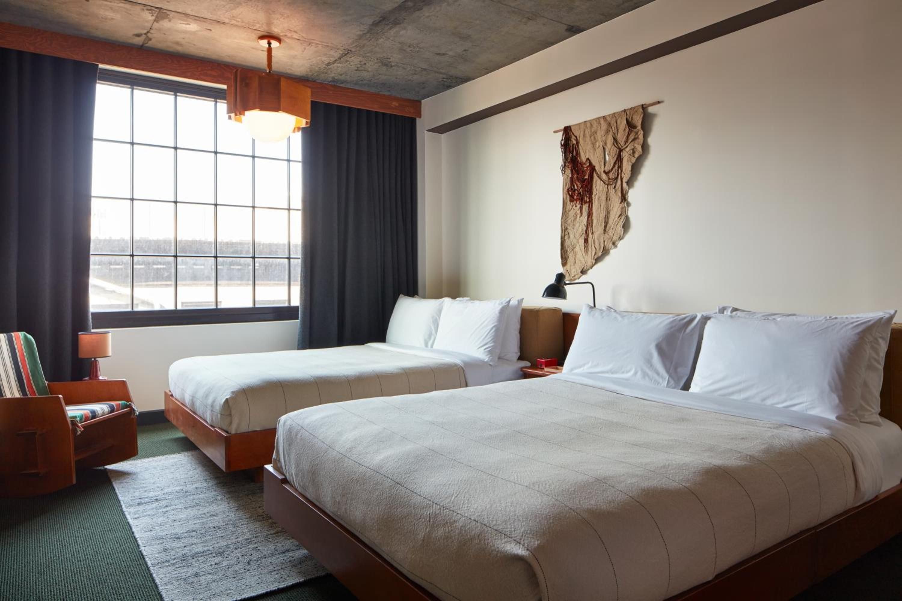 Industrial concrete ceilings meet warm wood frames in these thoughtfully appointed guest rooms, where handwoven textiles and forest-green accents create Brooklyn's coolest crash pad.