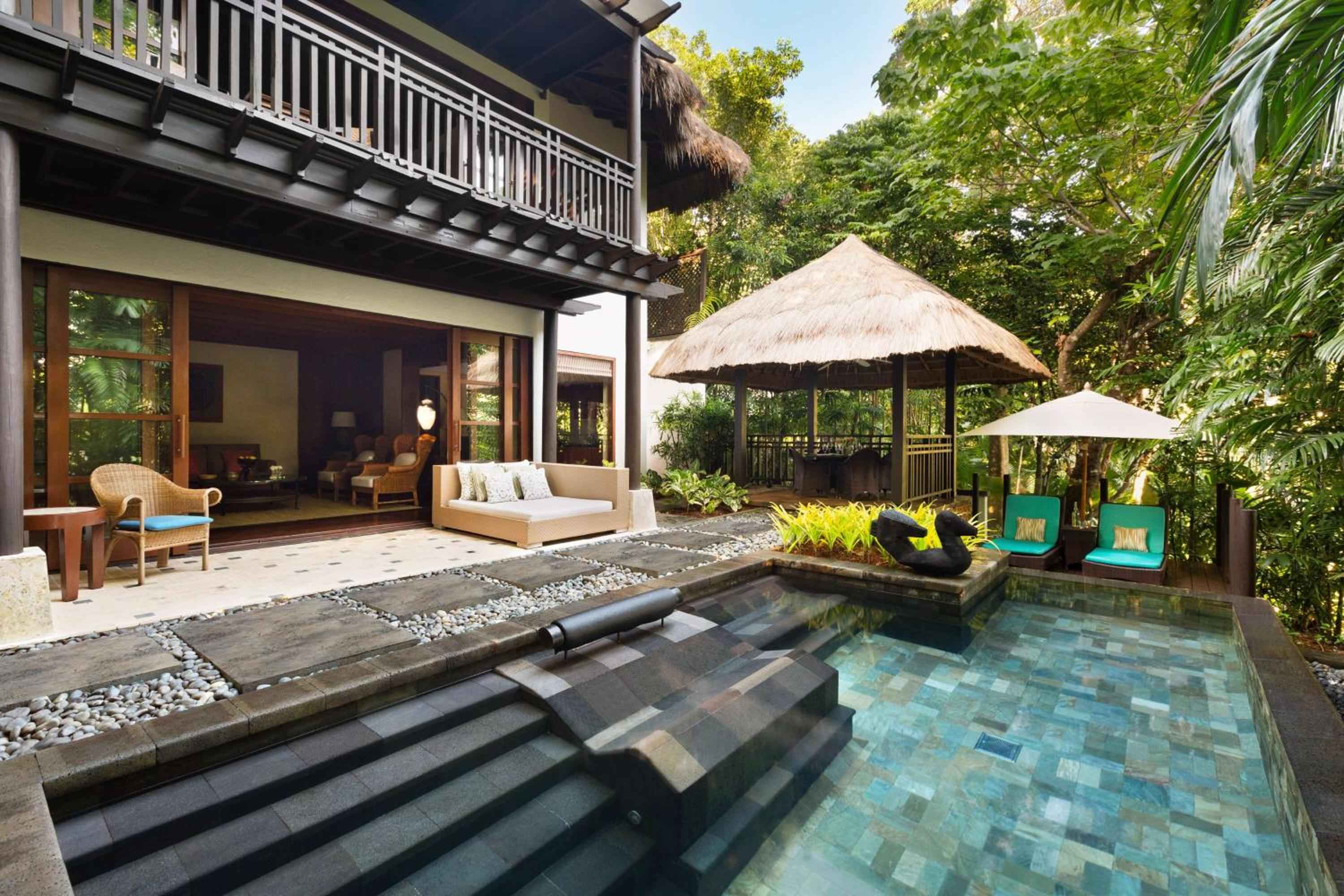 Private villa plunge pool reflects tropical light while thatched pavilions and scattered river stones create an intimate Balinese-inspired sanctuary steps from your suite.