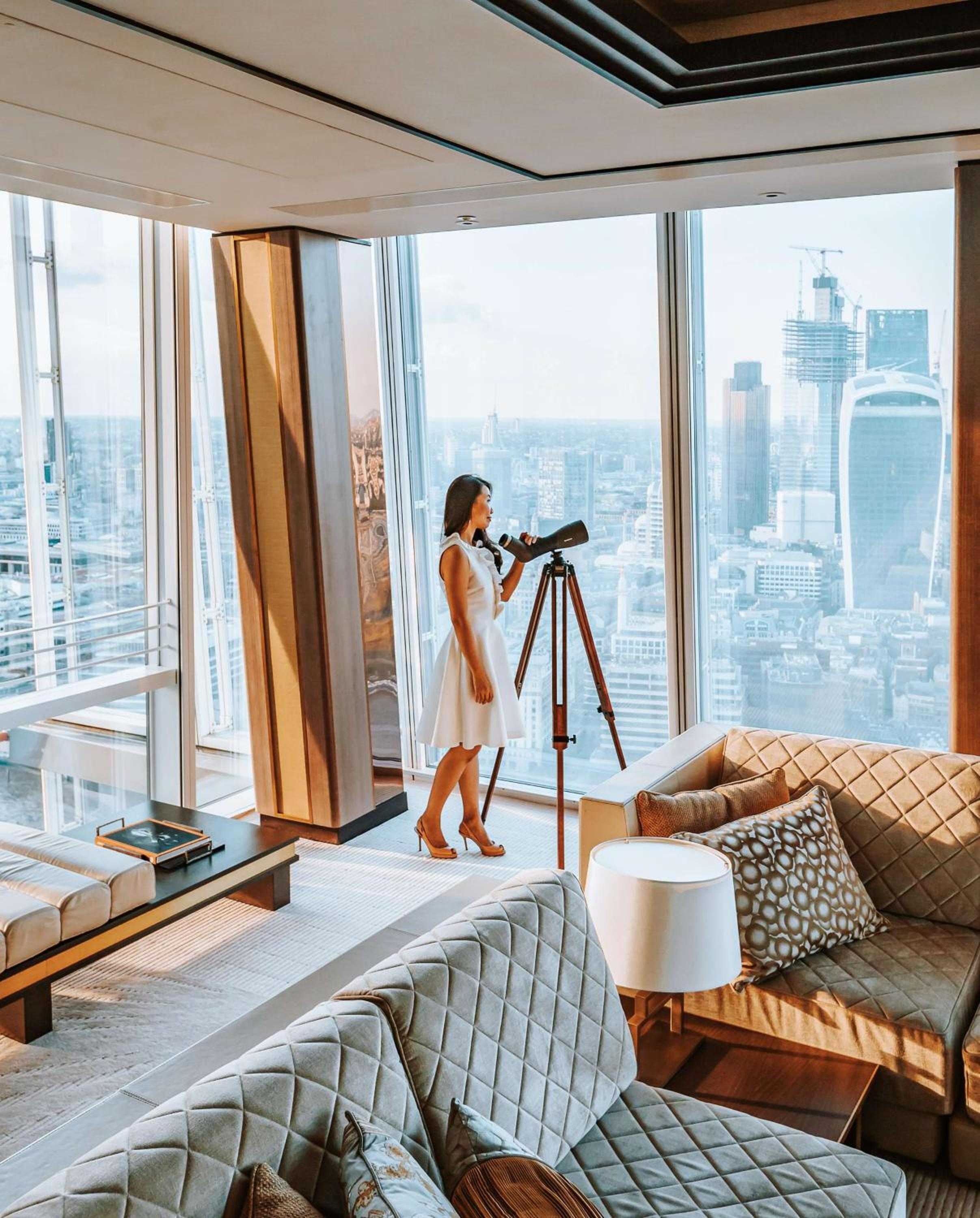 Floor-to-ceiling windows frame London's skyline from this luxurious suite, where quilted furnishings and warm wood create an intimate observatory high above the city.