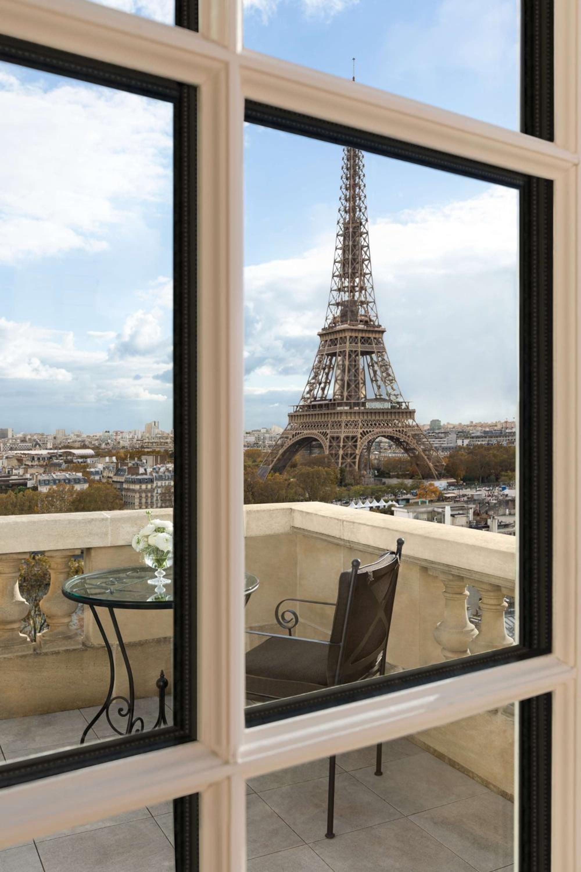 French windows frame an iconic Parisian tableau from this elegant suite, where intimate balcony dining meets postcard-perfect Eiffel Tower vistas across the City of Light.