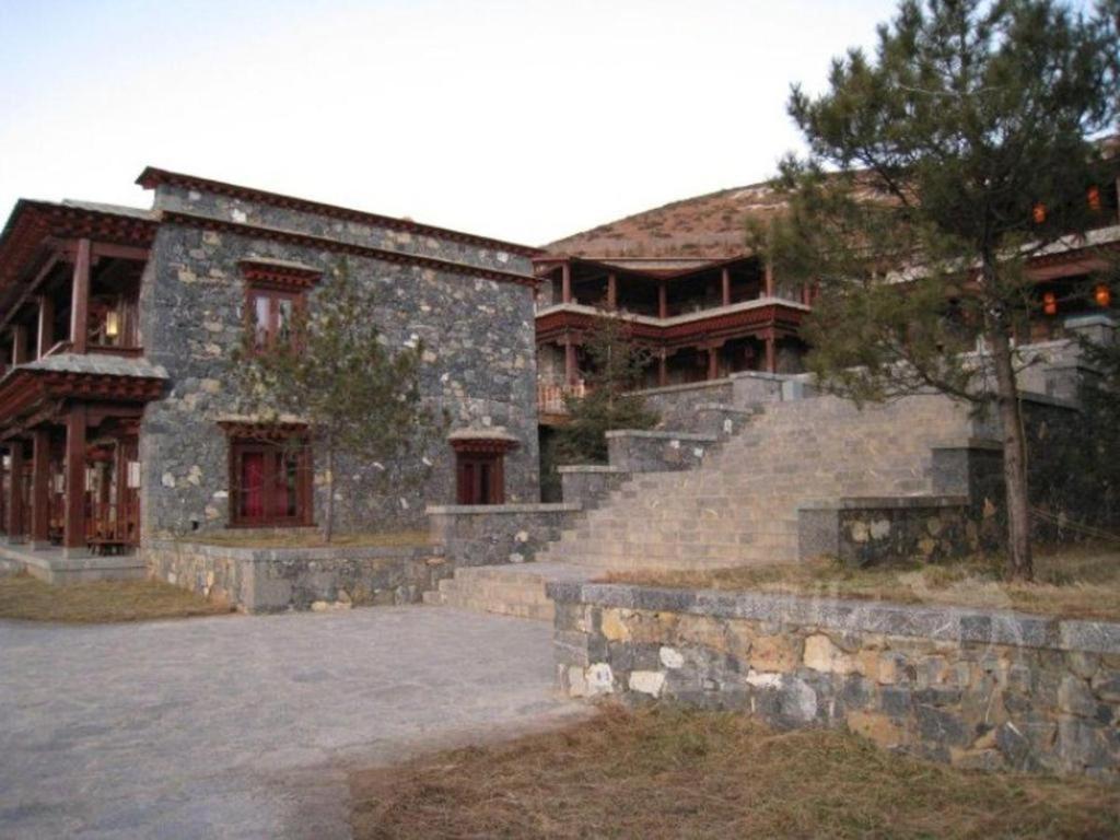 Stone walls and terracotta tiles create an intimate courtyard where ancient craftsmanship meets mountain serenity, steps leading to hidden chambers bathed in golden twilight.