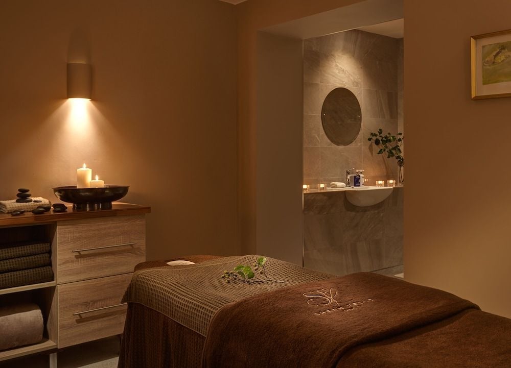 Candlelit serenity defines the treatment room, where warm earth tones and natural stone create an intimate wellness sanctuary overlooking the pristine basin.