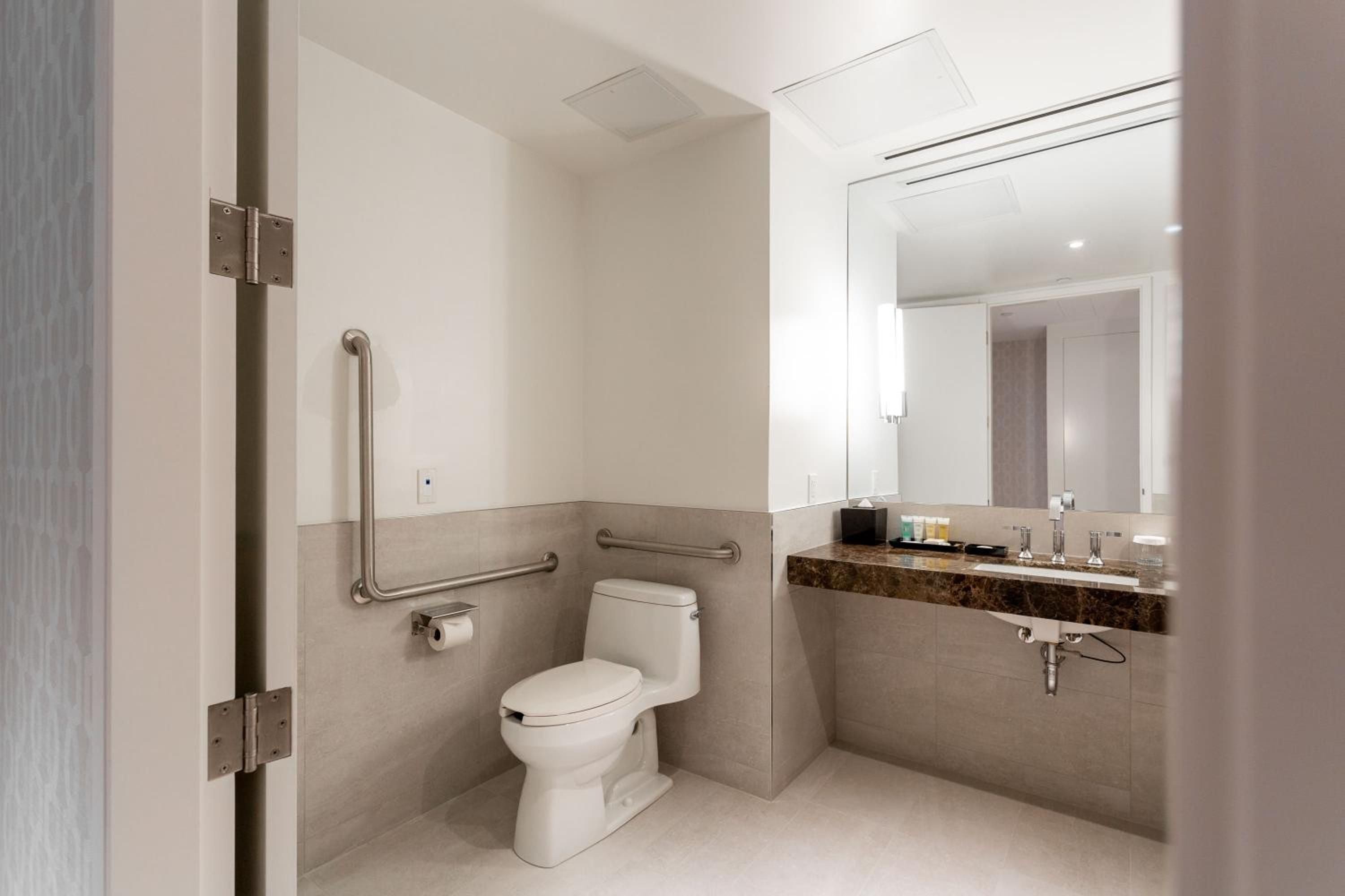 Accessible design meets modern elegance in thoughtfully appointed bathrooms, where polished granite counters and brushed steel fixtures create a spa-like sanctuary with universal appeal.