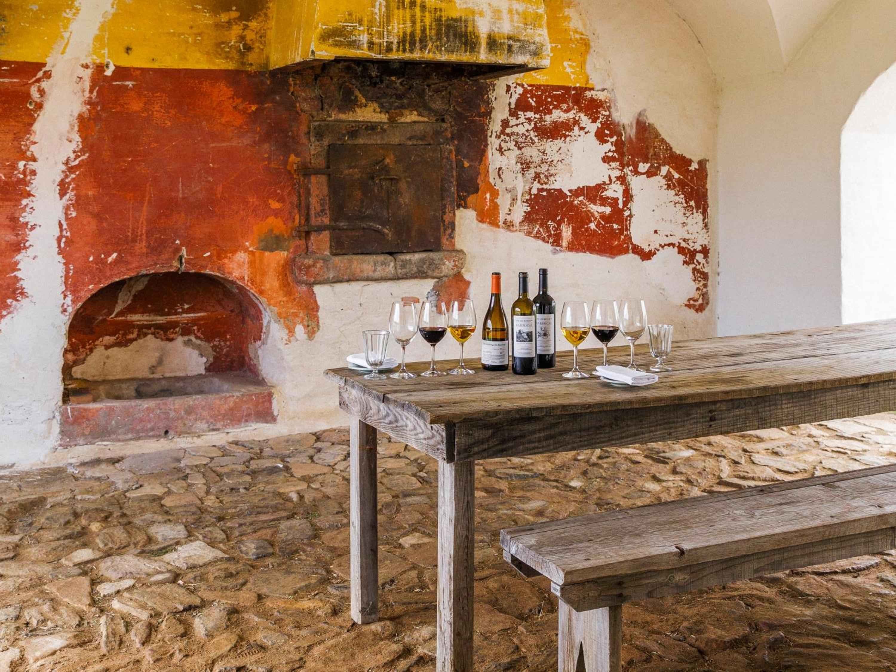 Weathered stone walls and rustic wooden tables create an intimate wine tasting corner, where centuries-old architecture mingles with carefully curated Portuguese vintages.