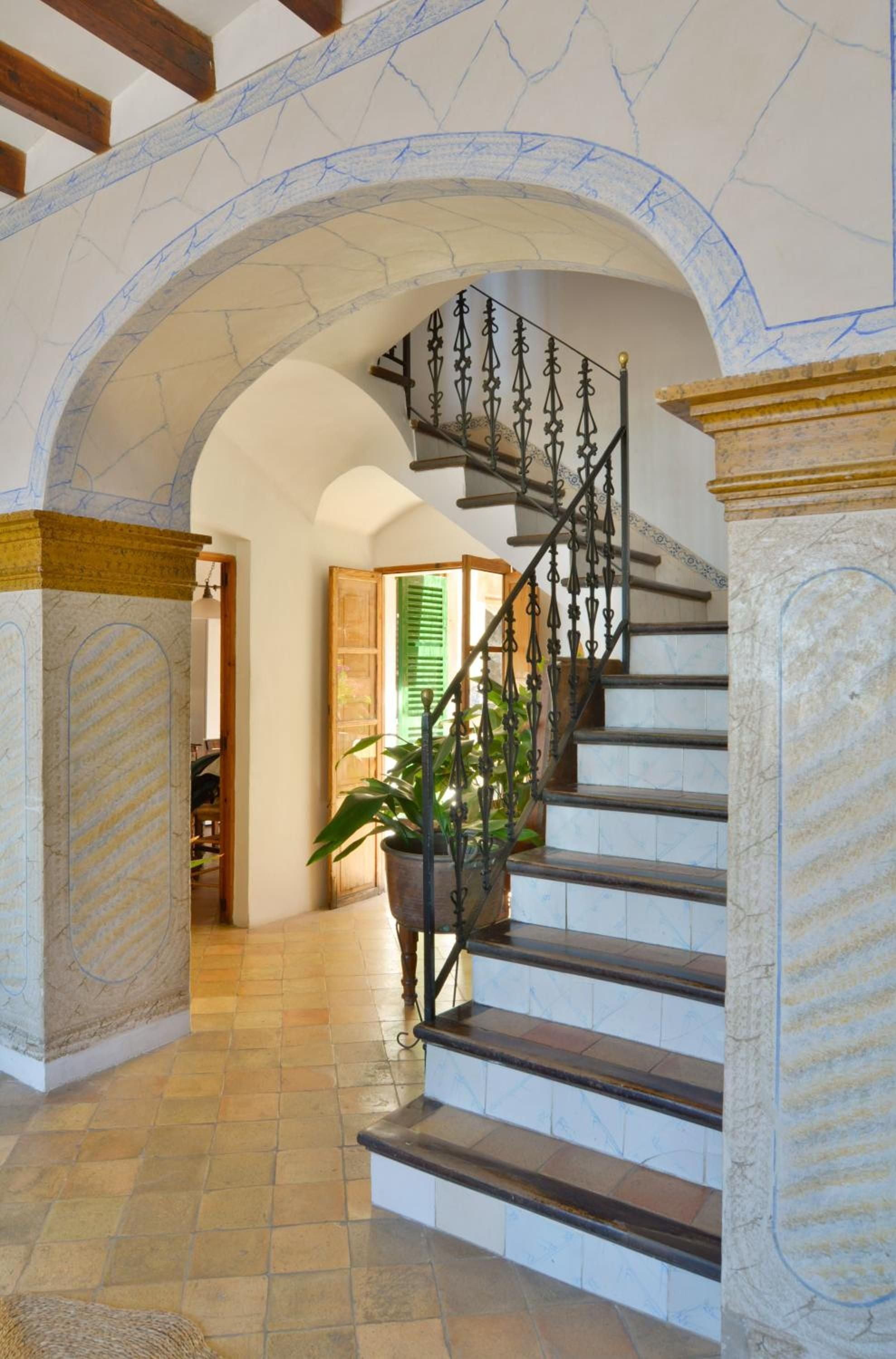 Handcrafted wrought iron spirals upward beneath stone arches, where Mallorcan marble meets exposed beams in this breathtaking fusion of Mediterranean heritage and refined luxury.