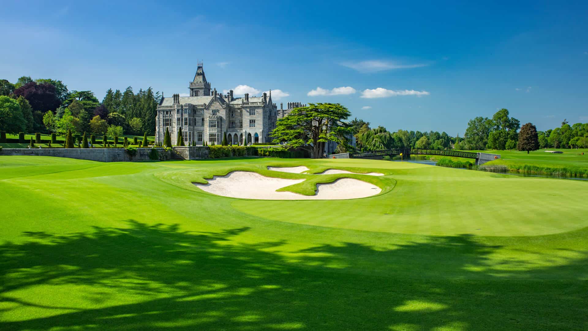 Emerald fairways sweep toward Adare Manor's limestone façade, where sand traps catch afternoon light and ancient cedars frame this championship golf paradise.