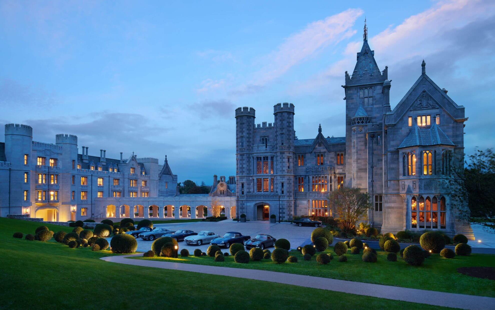 Gothic Revival towers and battlements glow against the Irish twilight as luxury cars gather beneath centuries-old stonework at this majestic Limerick estate.
