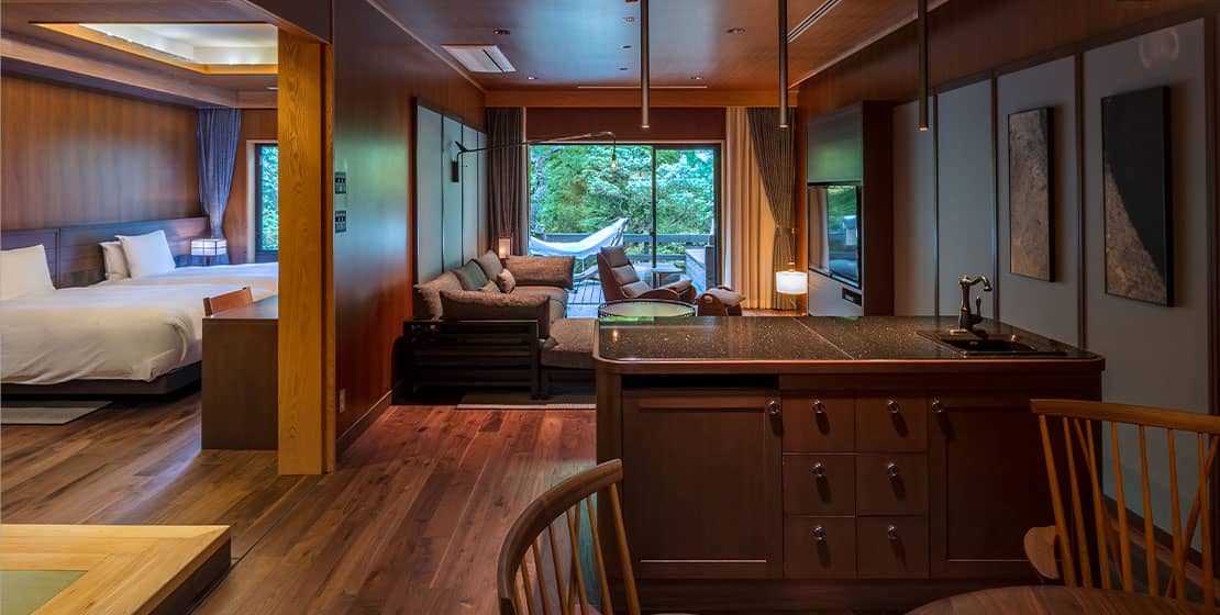 Rich walnut cabinetry and gleaming granite surfaces define this multi-room suite, where traditional Japanese craftsmanship meets contemporary luxury amid forest views.