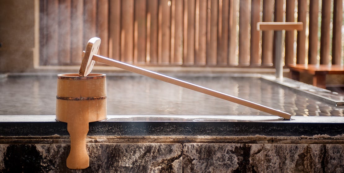 Bamboo ladles rest beside steaming onsen waters, where ancient purification rituals blend seamlessly with Hakone's timeless ryokan traditions and natural hot spring heritage.