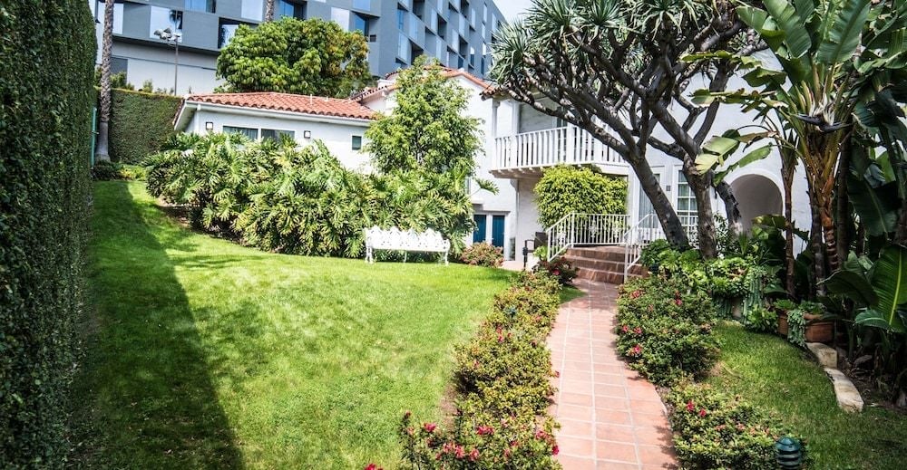 Lush tropical landscaping frames a charming Spanish-style villa, where terracotta walkways wind through manicured lawns and vibrant plantings create an intimate resort sanctuary.