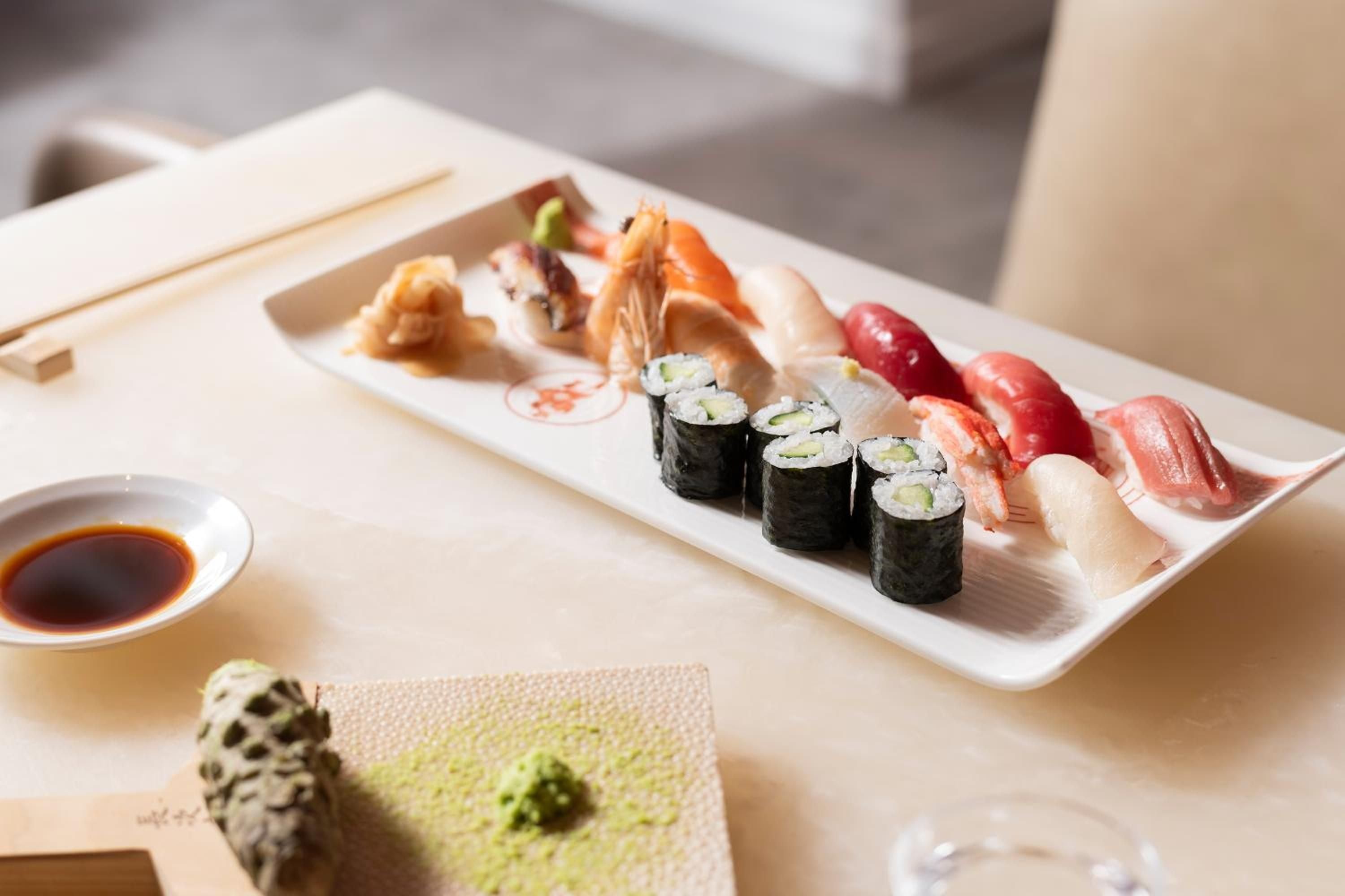 Artfully arranged sushi and sashimi showcase the precision of Japanese cuisine, complemented by wasabi and soy sauce on natural wood surfaces.