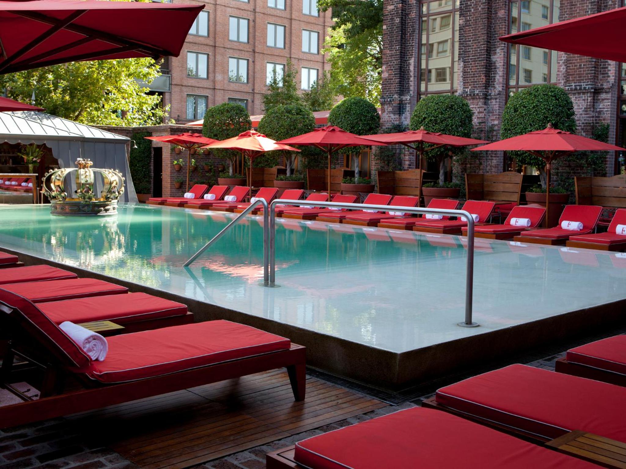 Crimson umbrellas cast geometric shadows over the infinity pool while Buenos Aires' brick facades frame this sophisticated urban oasis with its gleaming turquoise waters.
