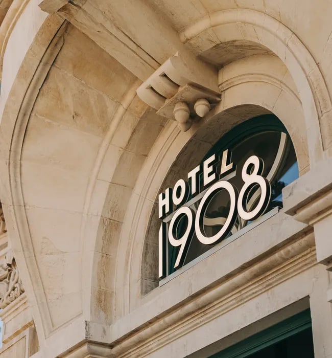 Carved limestone arches frame the hotel's elegant 1908 signage, where classical Portuguese architecture meets contemporary hospitality in Lisbon's historic center.