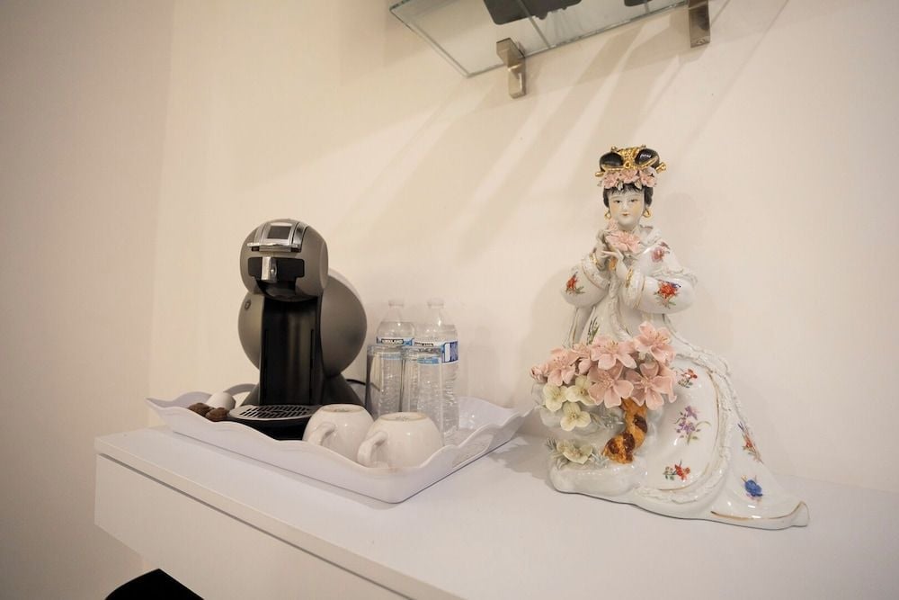Elegant porcelain figurines and fresh blooms create intimate vignettes alongside modern amenities, blending Hotel Emma's historic charm with contemporary comfort in thoughtfully curated guest rooms.