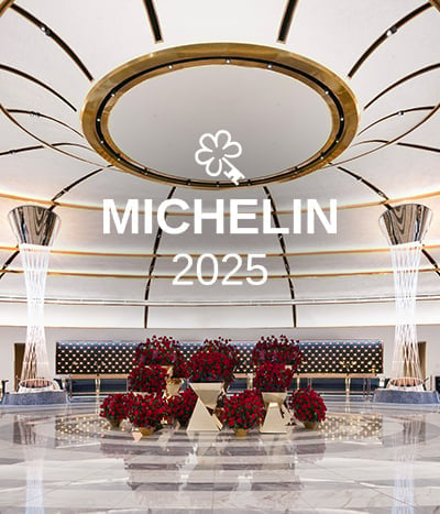 Soaring ceilings and marble floors create a grand entrance beneath the golden dome, where crimson floral arrangements add warmth to contemporary Vegas luxury.