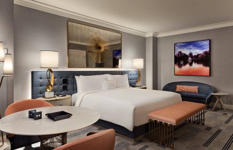 Plush coral seating and brass accents create intimate conversation areas in this sophisticated suite, where geometric patterns and warm lighting invite lingering conversations.