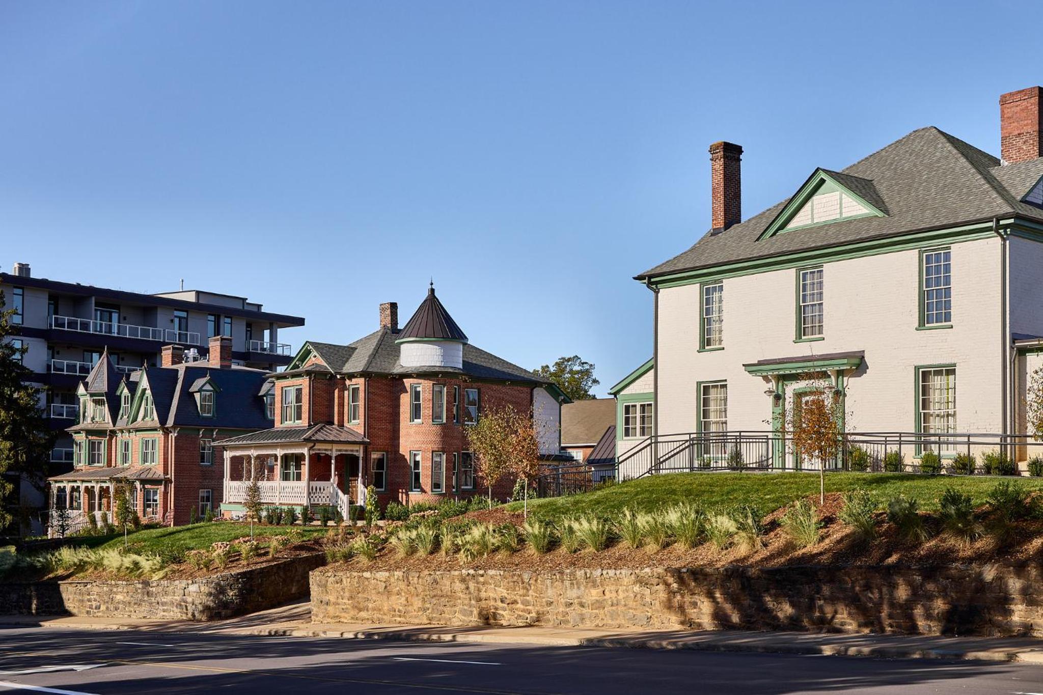 Victorian brick facades and contemporary stone terraces create an enchanting streetscape where historic charm meets modern hospitality beneath Carolina's endless blue sky.