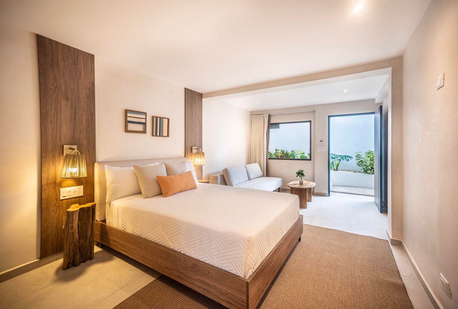 Natural wood accents and woven textures create serene intimacy, while sliding doors frame tropical greenery beyond this thoughtfully appointed suite.