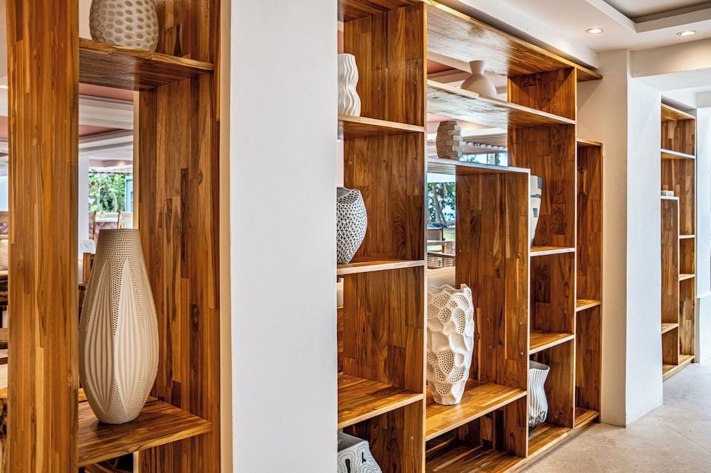Geometric shelving displays sculptural ceramics and woven vessels, creating an artful divider where warm teak meets contemporary design in the hotel's sophisticated common areas.