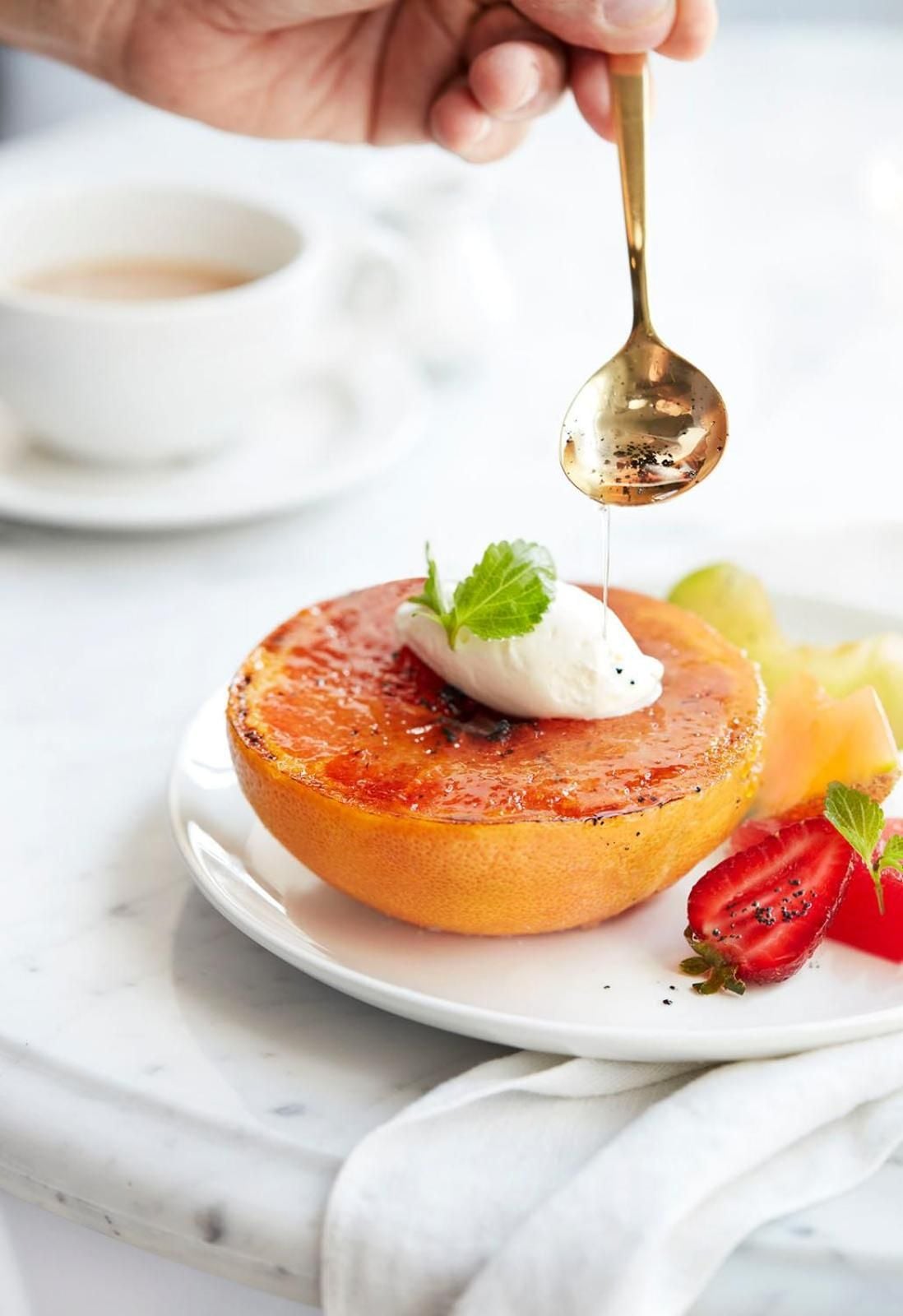 Golden honey drizzles over caramelized grapefruit brûlée, garnished with fresh cream and mint—a stunning finale to breakfast at this sophisticated downtown Toronto retreat.