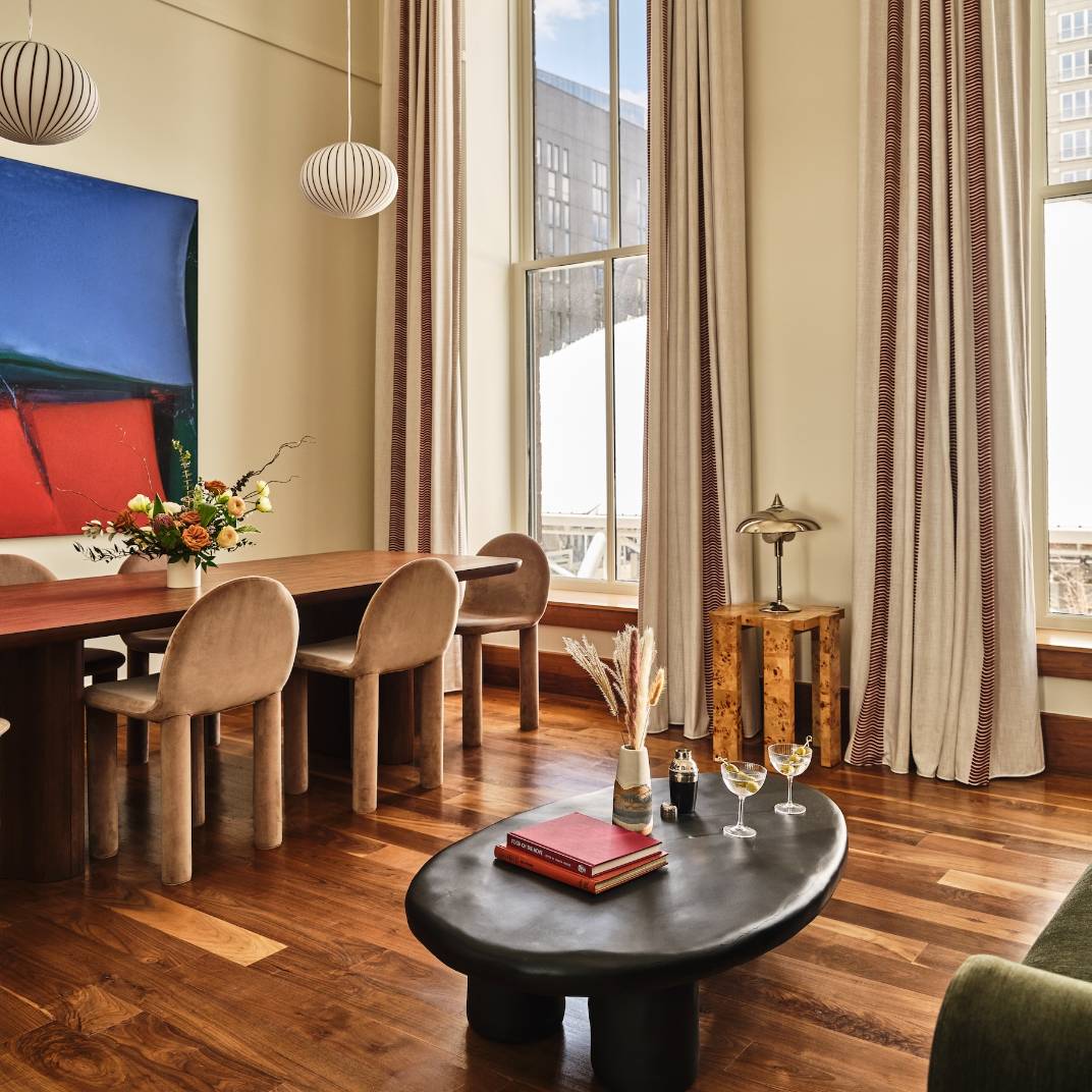 Warm wood floors meet sculptural pendant lights in this Union Station suite, where curved dining chairs frame snow-dusted city views through soaring windows.