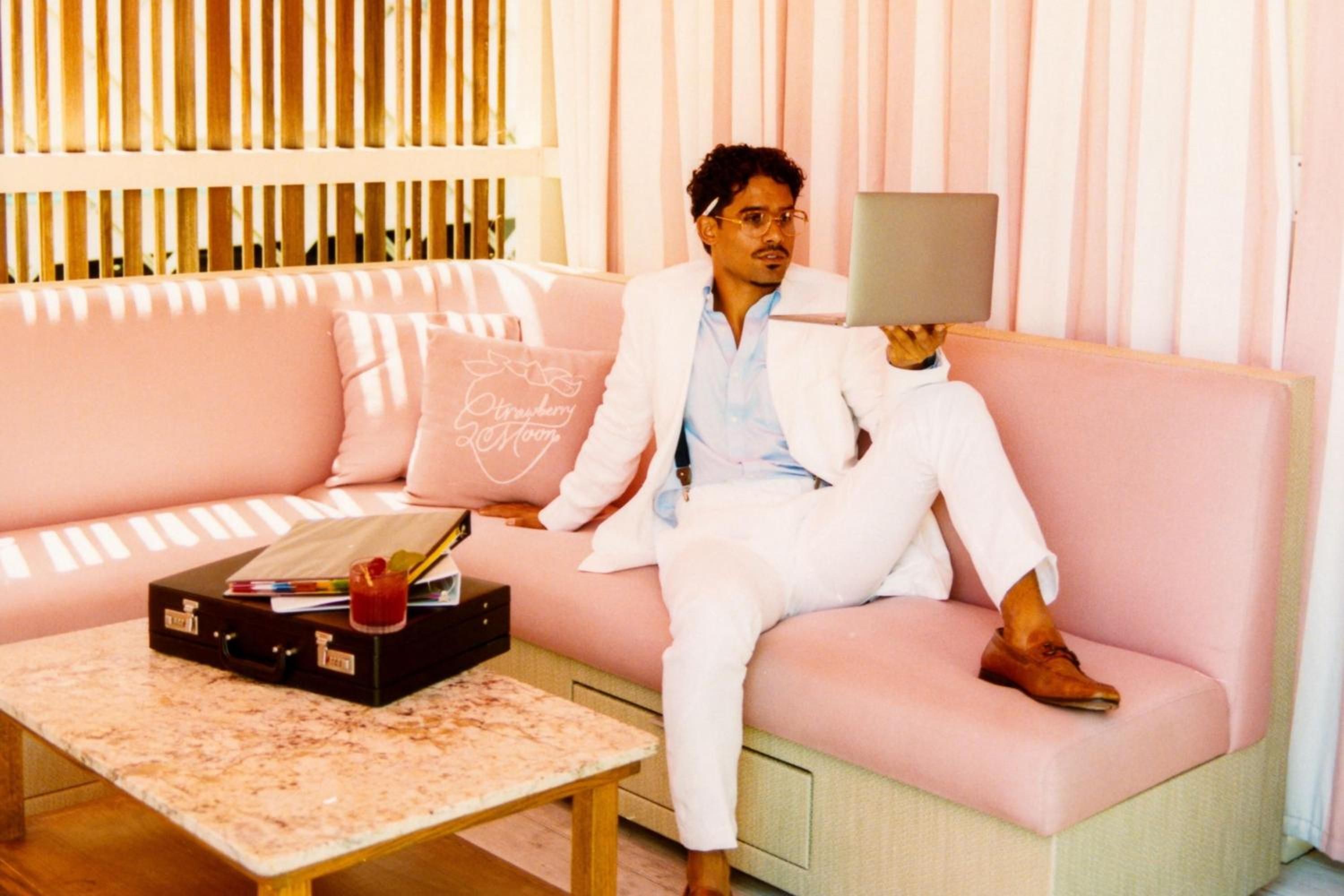 Millennial pink furnishings and warm wood accents create a Miami Beach dreamscape where guests lounge laptop-in-hand, basking in filtered sunlight and retro-chic vibes.