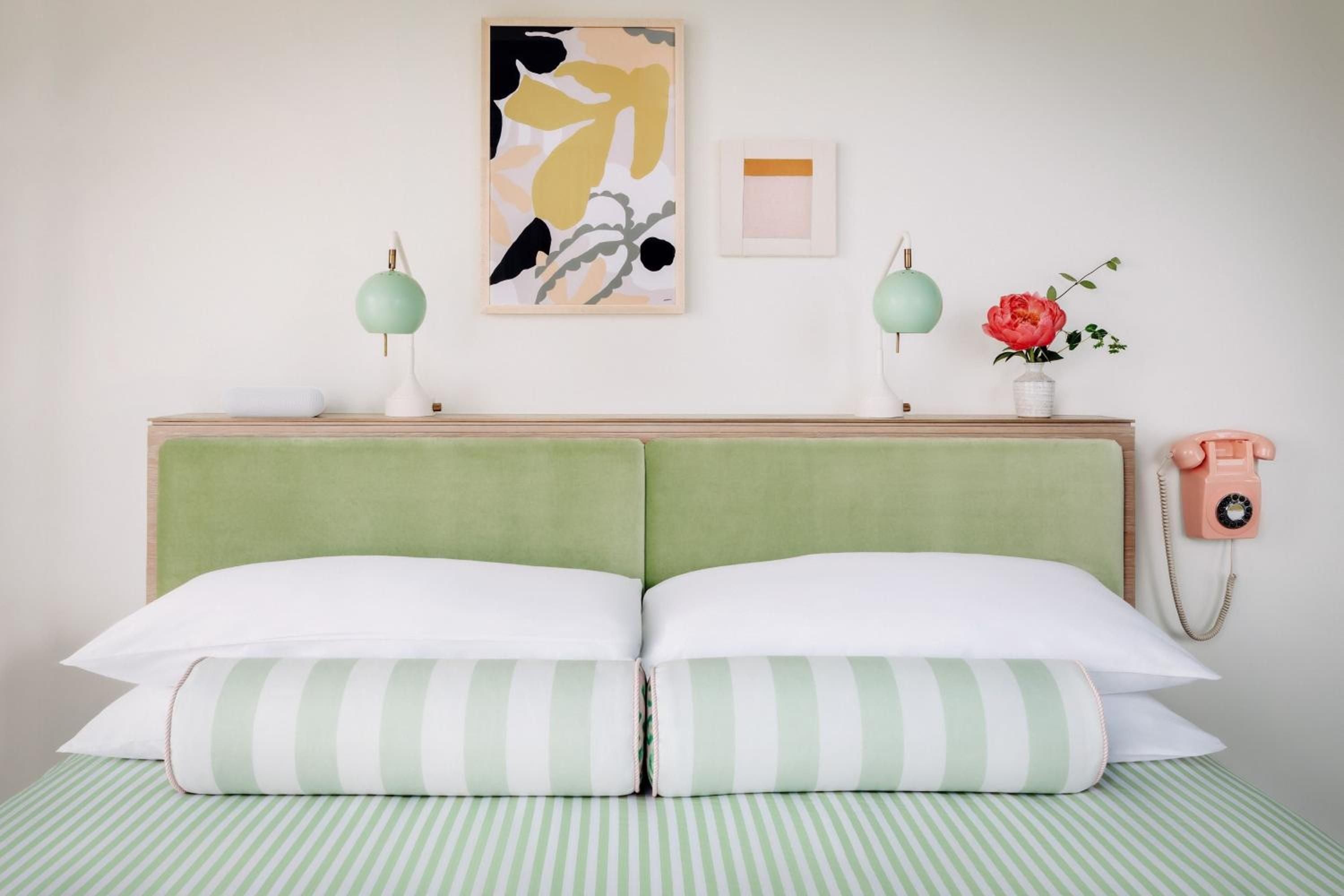 Sage green velvet headboards and mint-striped linens create a dreamy, retro-chic sanctuary, while playful touches like rotary phones add whimsical charm to every corner.