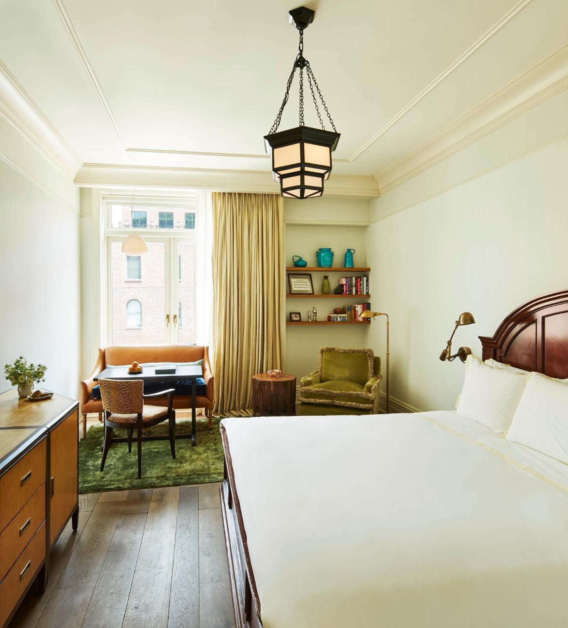 Warm amber light filters through tall windows onto rich wood floors, where vintage leather meets olive velvet in this thoughtfully curated corner of downtown tranquility.