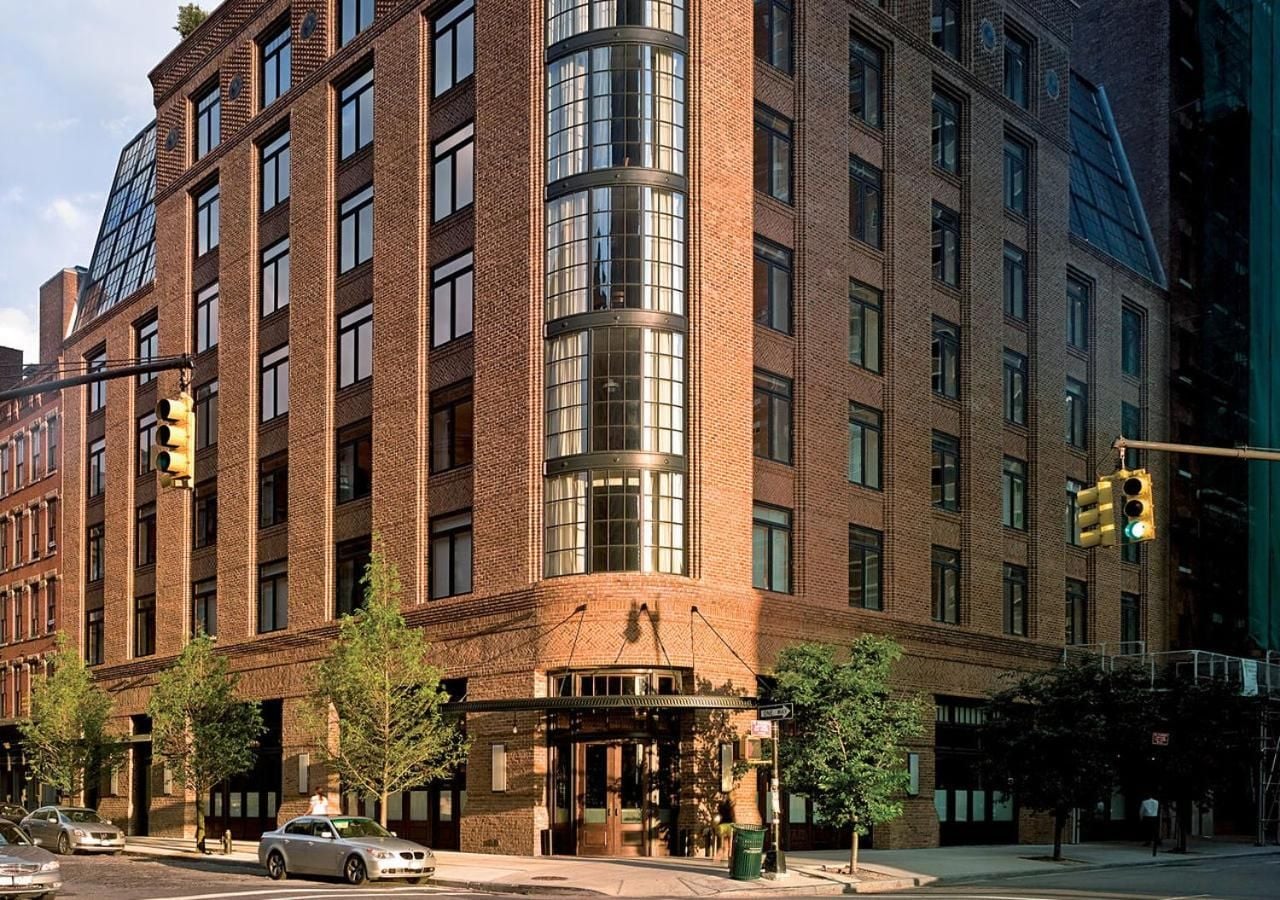Red brick facade curves gracefully around the corner, where industrial heritage meets intimate luxury in this discreet Tribeca sanctuary amid cobblestone streets.