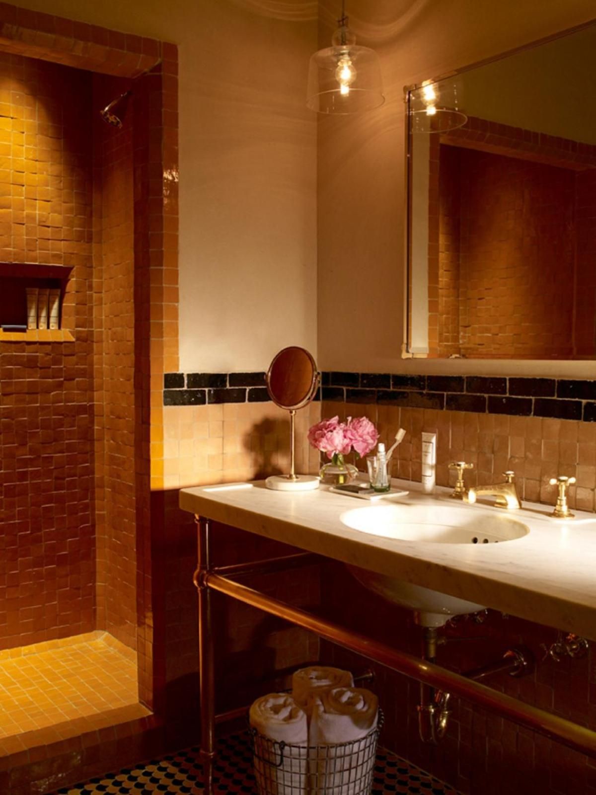 Warm Edison bulb fixtures cast honeyed light across handcrafted tiles and brass fittings, creating an intimate sanctuary where industrial chic meets old-world craftsmanship.
