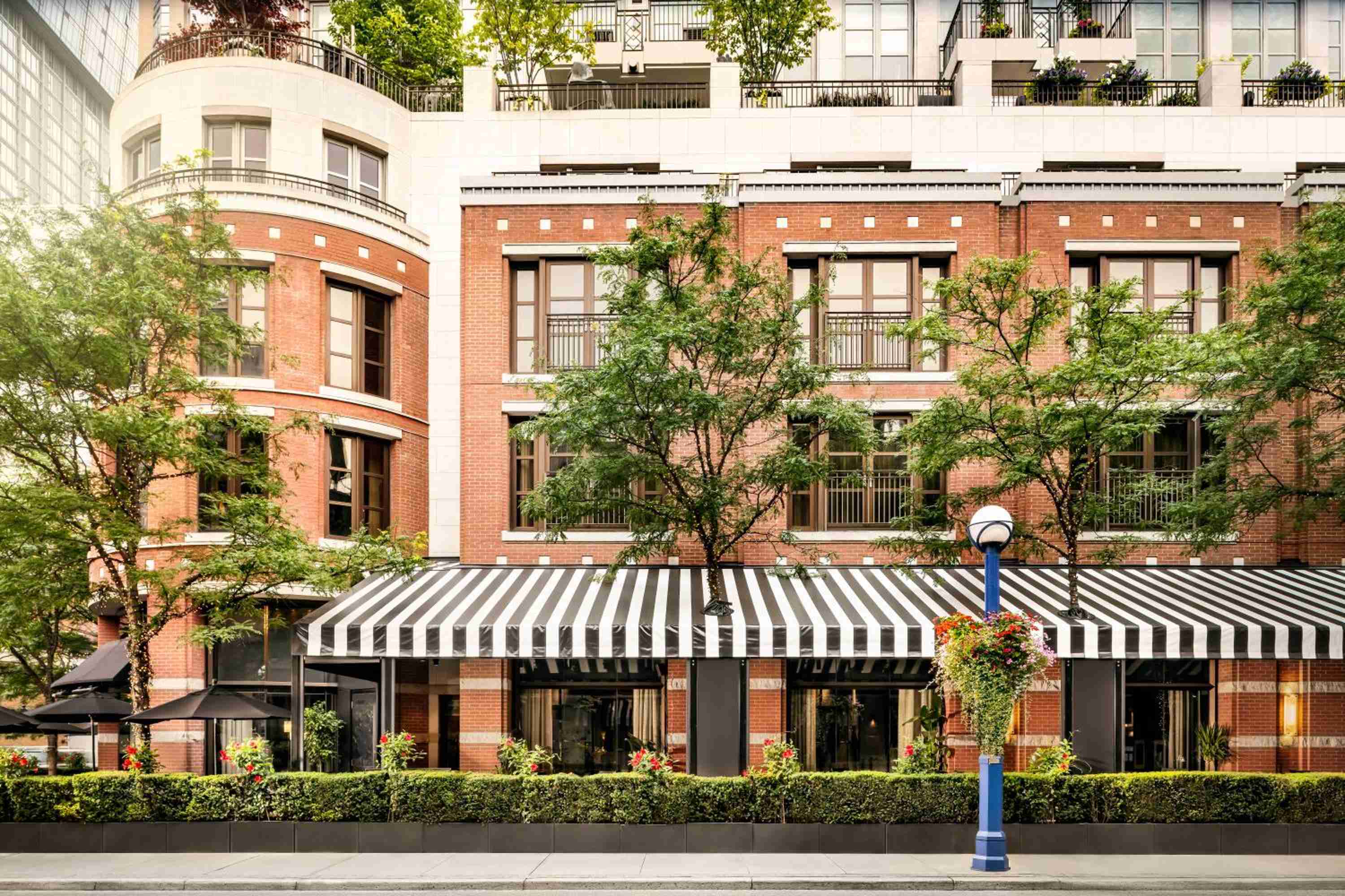 Red brick facade and black-and-white striped awnings create an intimate streetscape where European elegance meets Toronto's sophisticated Yorkville neighborhood charm.
